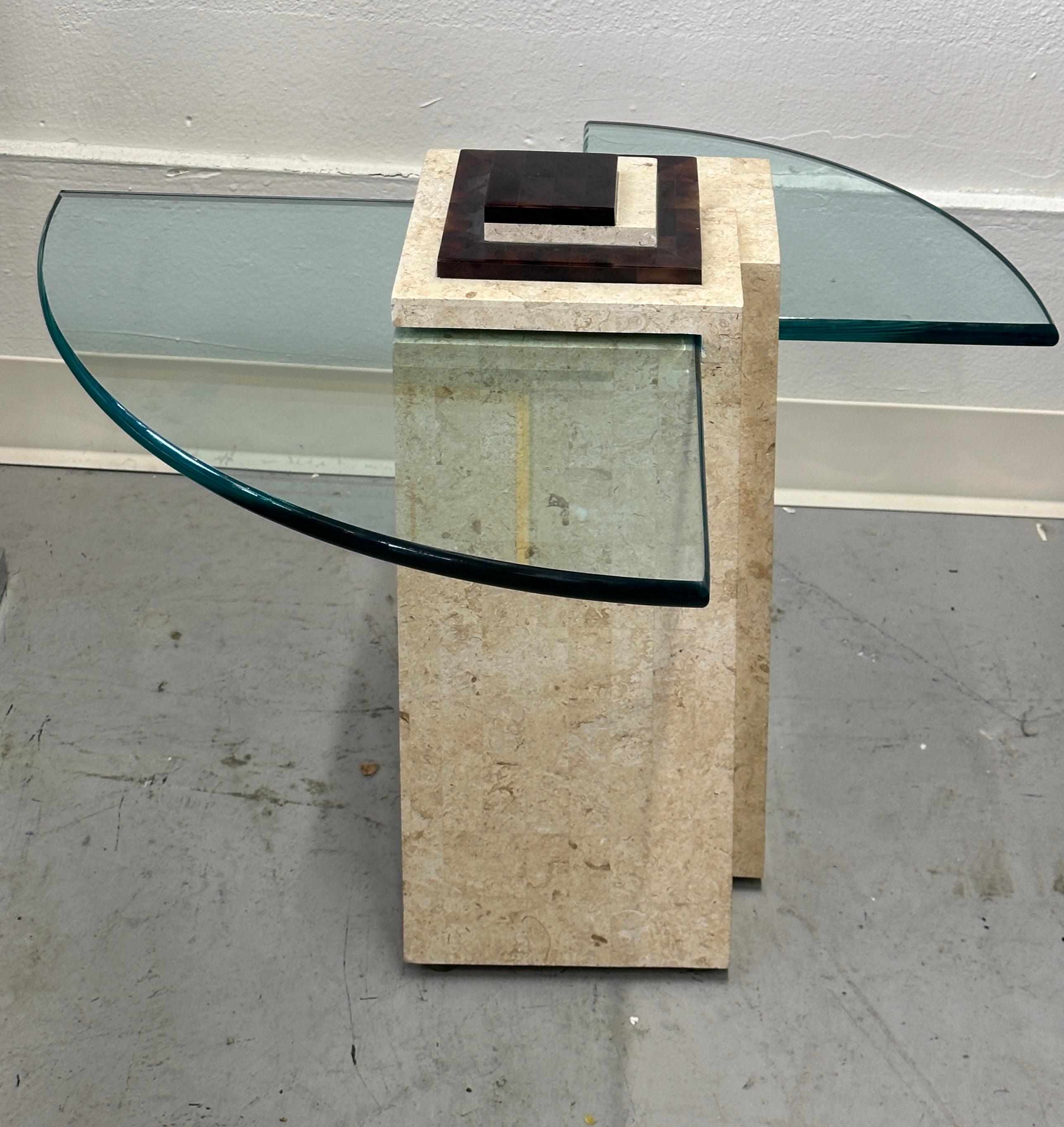 A lovely side table cleverly engineered with two triangular pieces of glass set into a square column of travertine and horn tessellated pieces layered on top. Marked with a label underneath; made in the Philippines. The table is attributed to