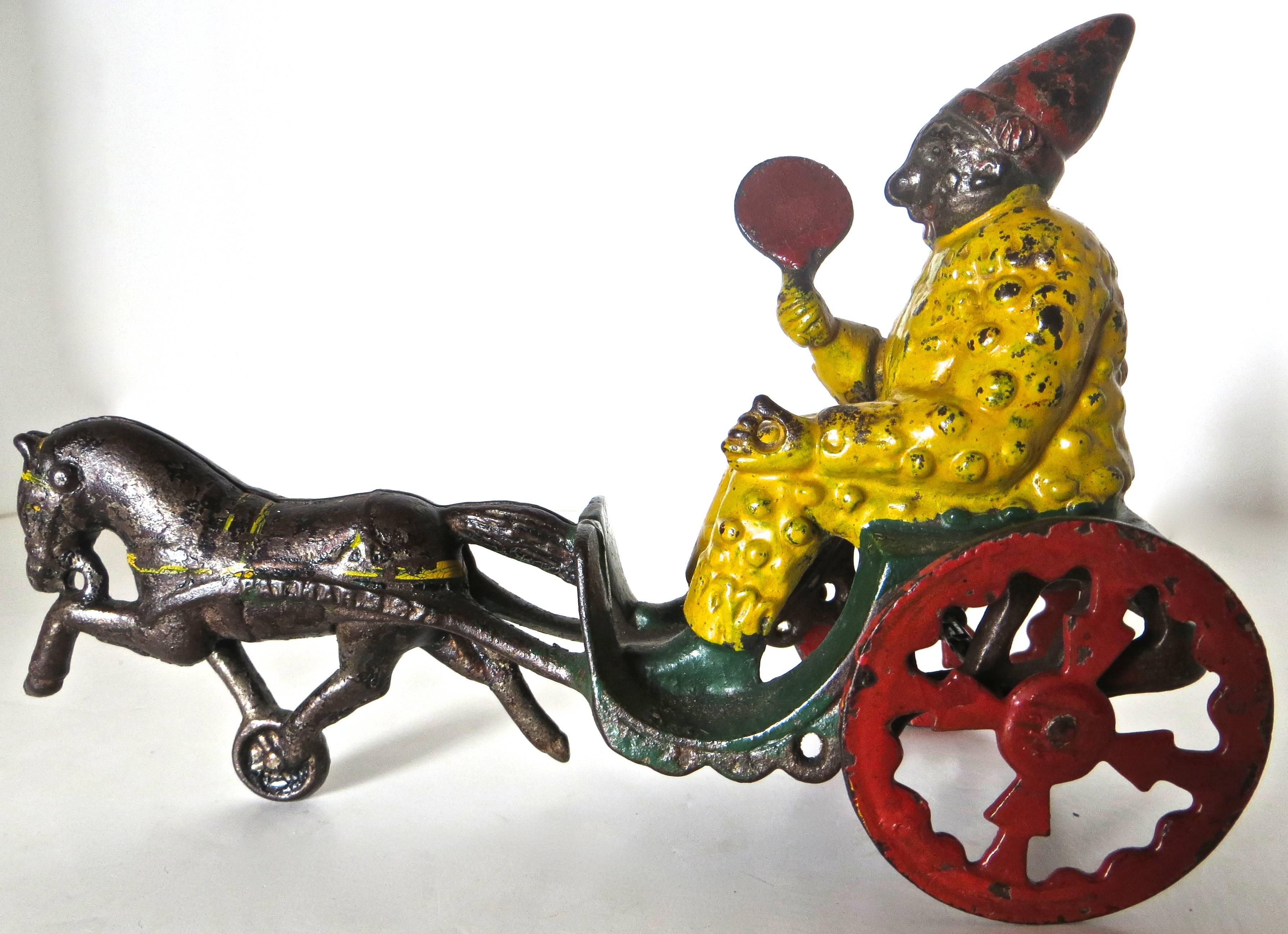 Whimsical cast iron horse drawn articulated toy that depicts a clown who, when rolled across a flat surface, fans himself by waving his right arm back and forth. It was manufactured by the 