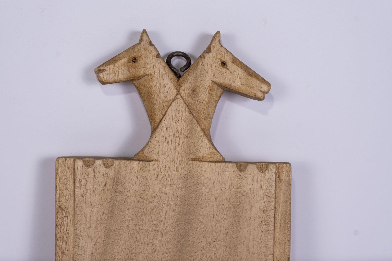 Horse head crested French cutting board dating to the mid-to-early 20th century. Double horse head motif crest hand-carved at top of board.