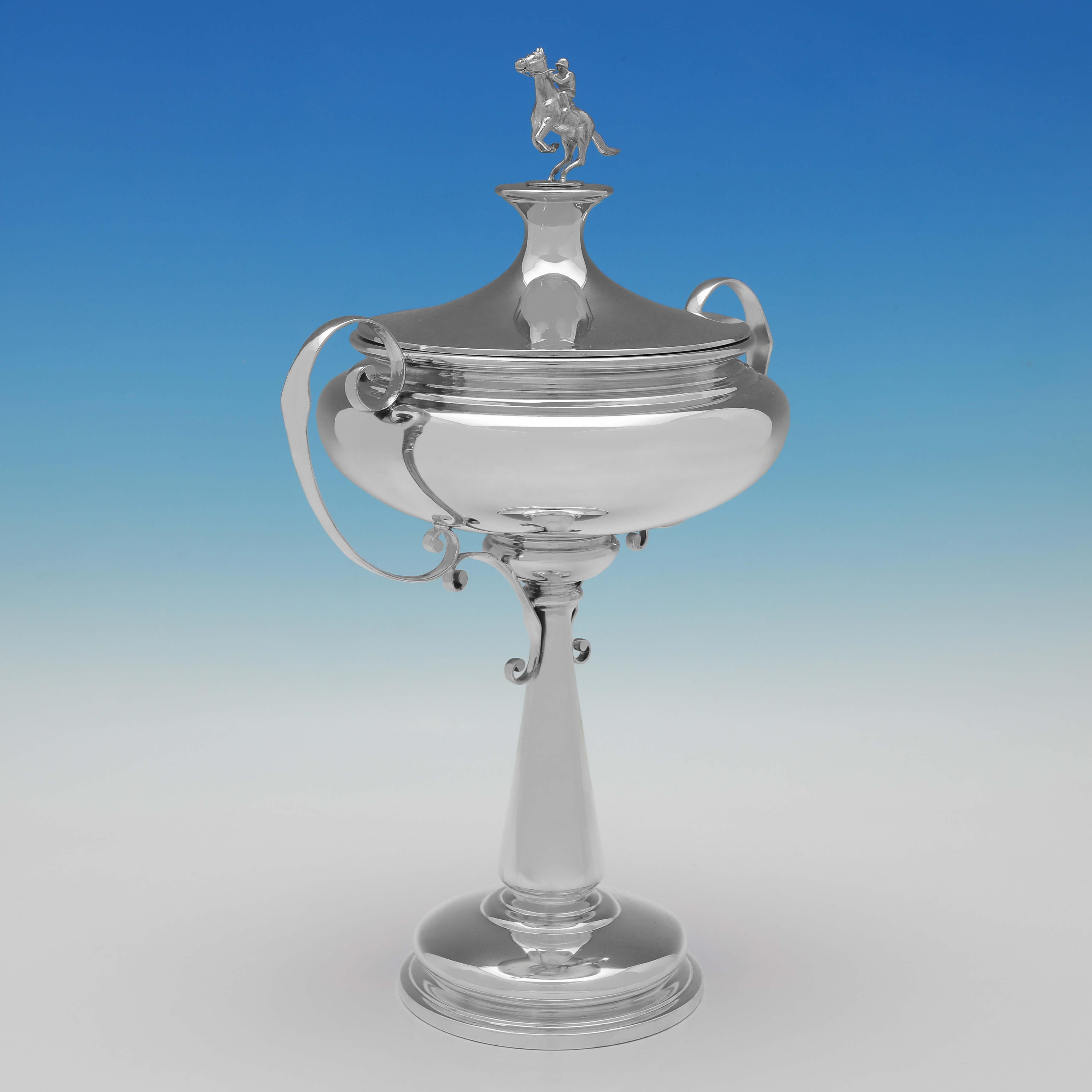 Hallmarked in Sheffield in 1925 by Walker & Hall, this handsome, Sterling Silver Trophy Cup, features scroll handles, and a horse and jockey finial. 

The trophy measures 15