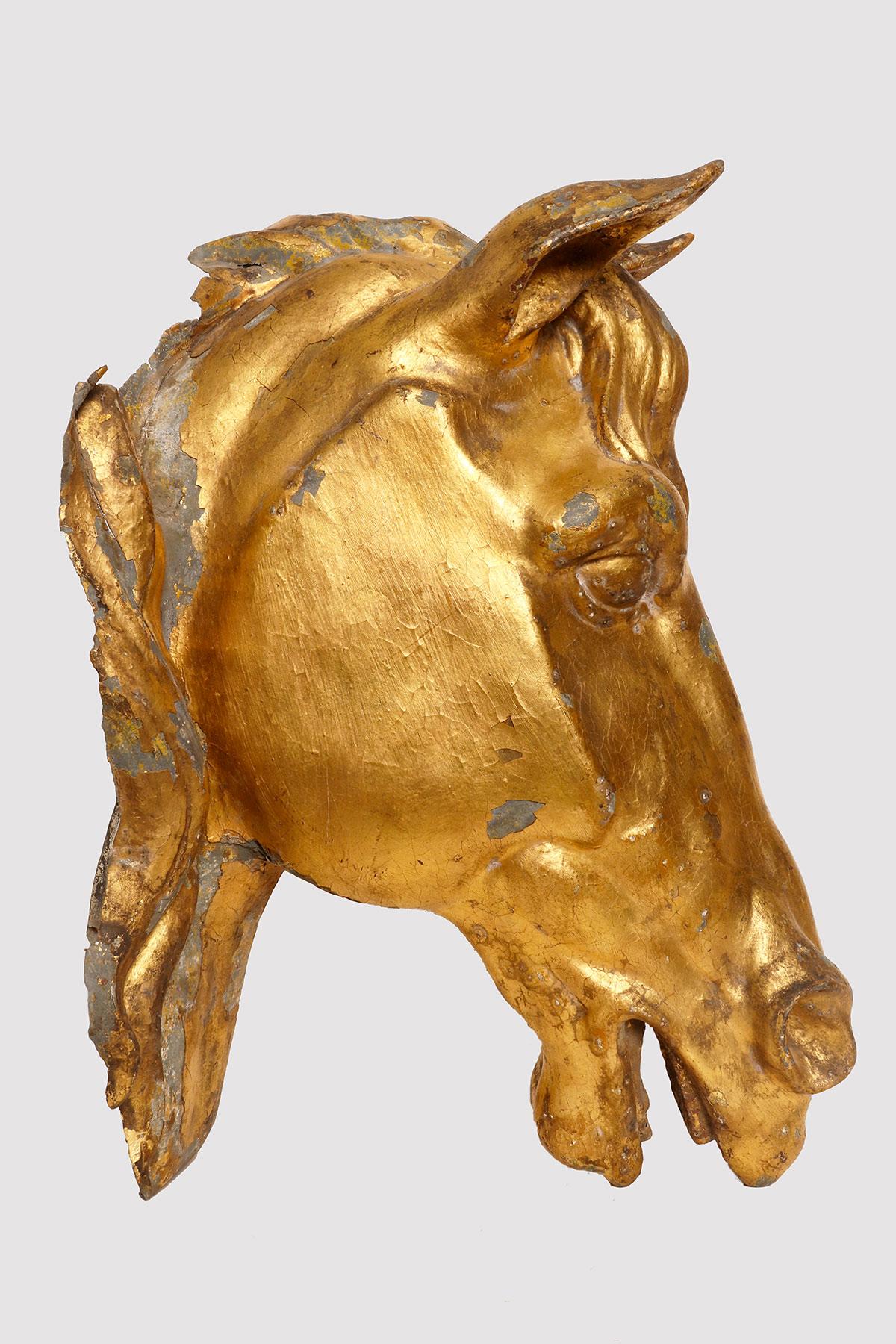 Skulptur aus vergoldetem Zinkblech mit Blattgold, die einen Pferdekopf darstellt. Die Skulptur ist vollständig geprägt und zeigt zwei Mähnenflügel. Der Pferdekopf war ein dekorativer Teil eines englischen Landhauses, vielleicht besser als der Stall,