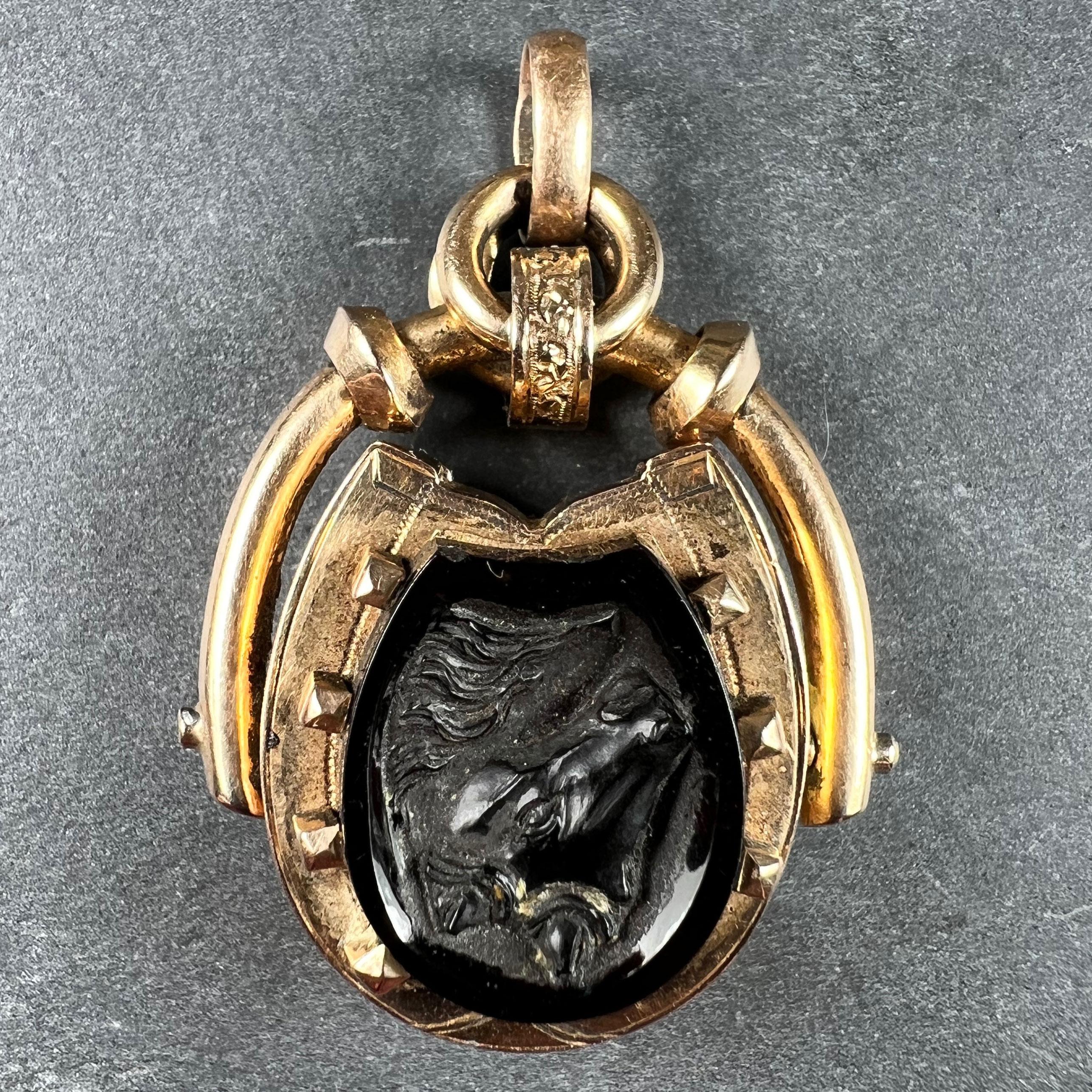 An 18 karat (18K) rose gold pendant locket with rotating horseshoe design set to one side with an onyx plaque, to the other with an onyx cameo of a horse's head. Opening to reveal a round photo locket to one side. Stamped with the owl mark for