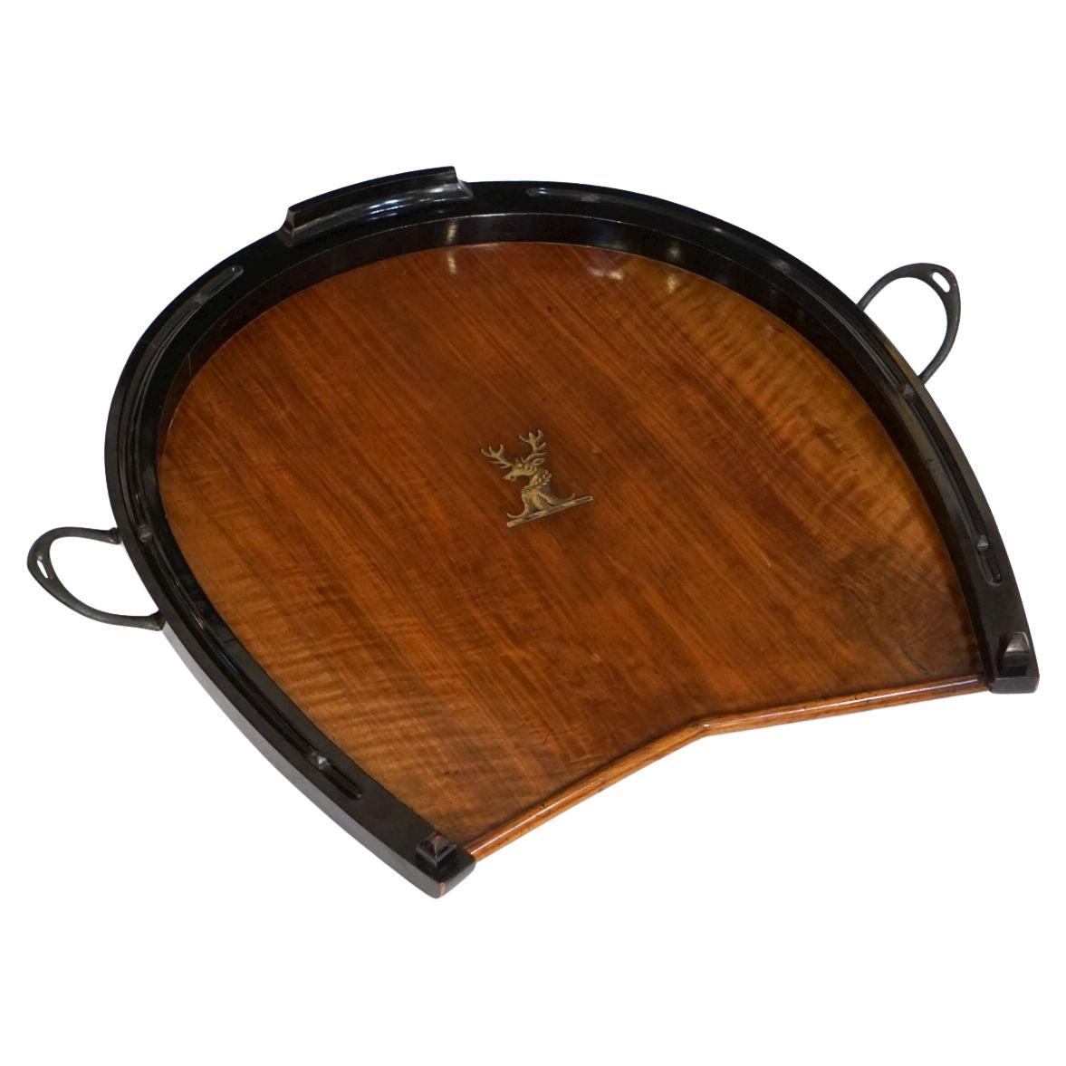 A fine English serving or display tray from the Edwardian Era featuring a horseshoe-shaped design of beautifully patinated walnut with ebonized wood accents, with two opposing handles and nail-head studs of iron around the circumference, and an