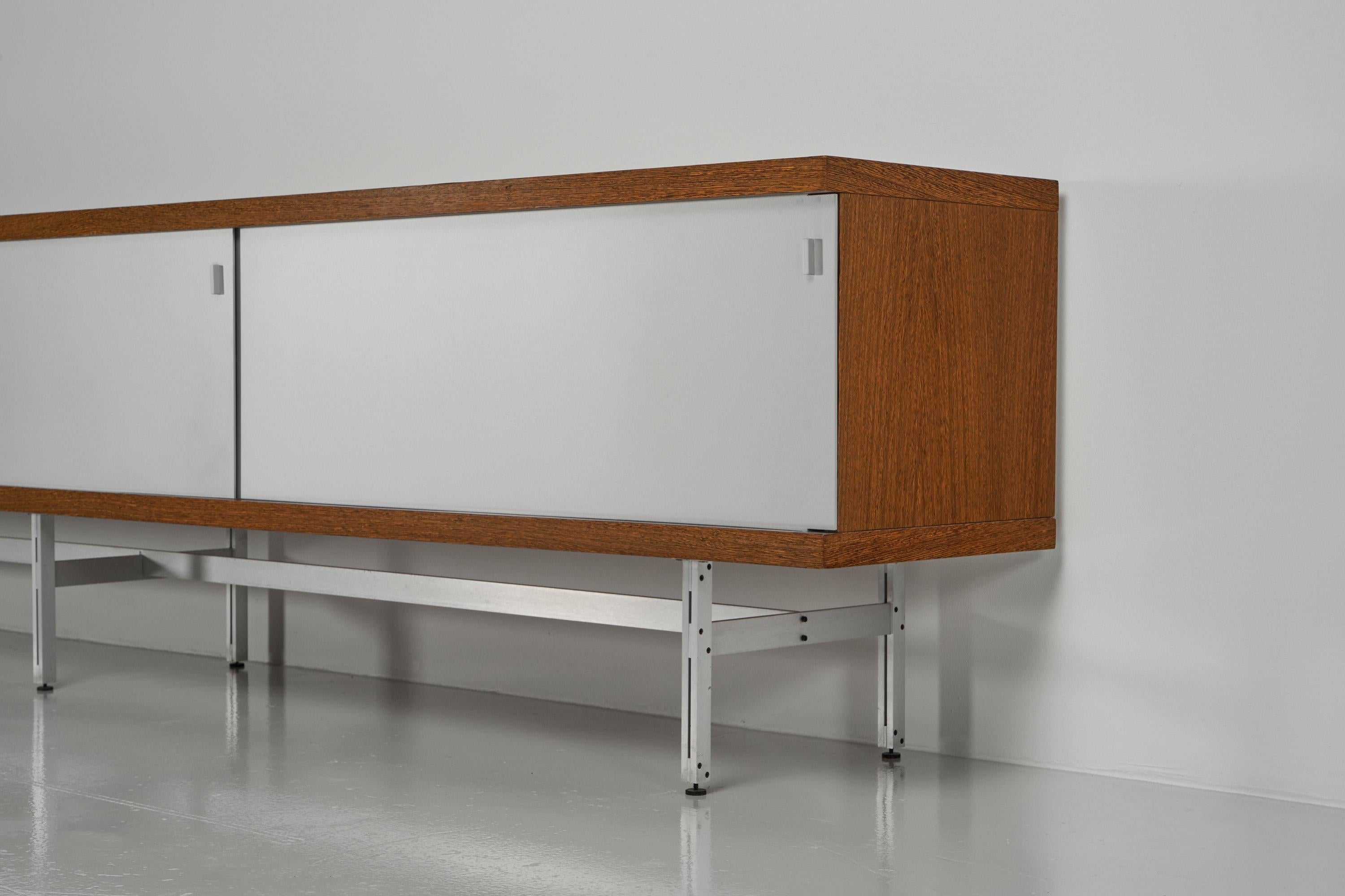 A minimalistic model 1730 sideboard designed by Horst Brüning and manufactured by Behr Germany 1960. This fantastic large sized sideboard has a wenge cabinet, finished with 3 aluminium sliding doors and it has a white painted and laminated inside.