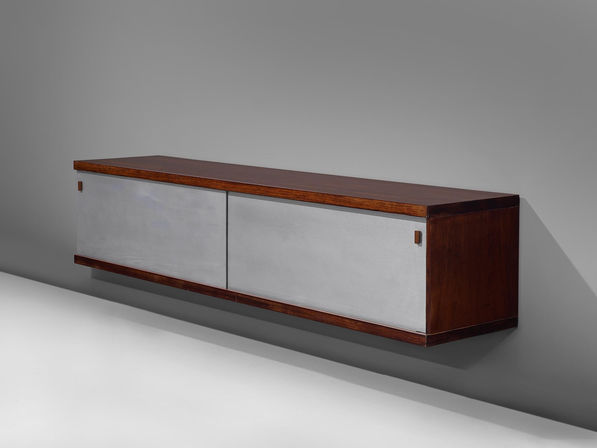 Horst Brüning for Behr, wall-mounted credenza, rosewood, aluminum and wood, Germany, 1960.

This geometric credenza holds a rosewood case and a brushed metal frame. The sliding doors are made of grey Formica and have geometric grips. The rosewood