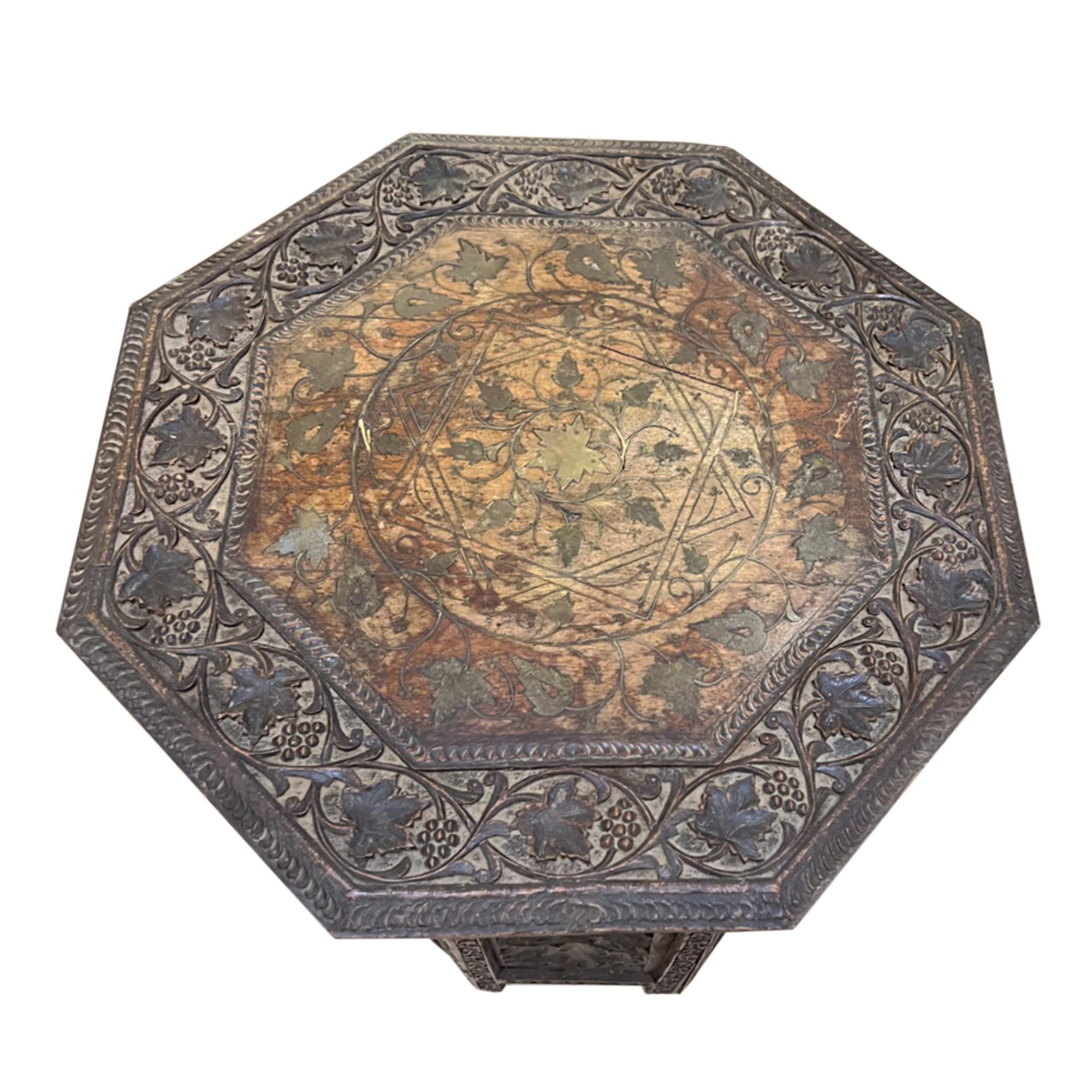 Highly decorative and beautifully carved - this occasional table was made in India in the early 20th century. 

Please have a close look at all our photographs to see the detail in both the carved wood and the brass inlay. 

Our restorer has