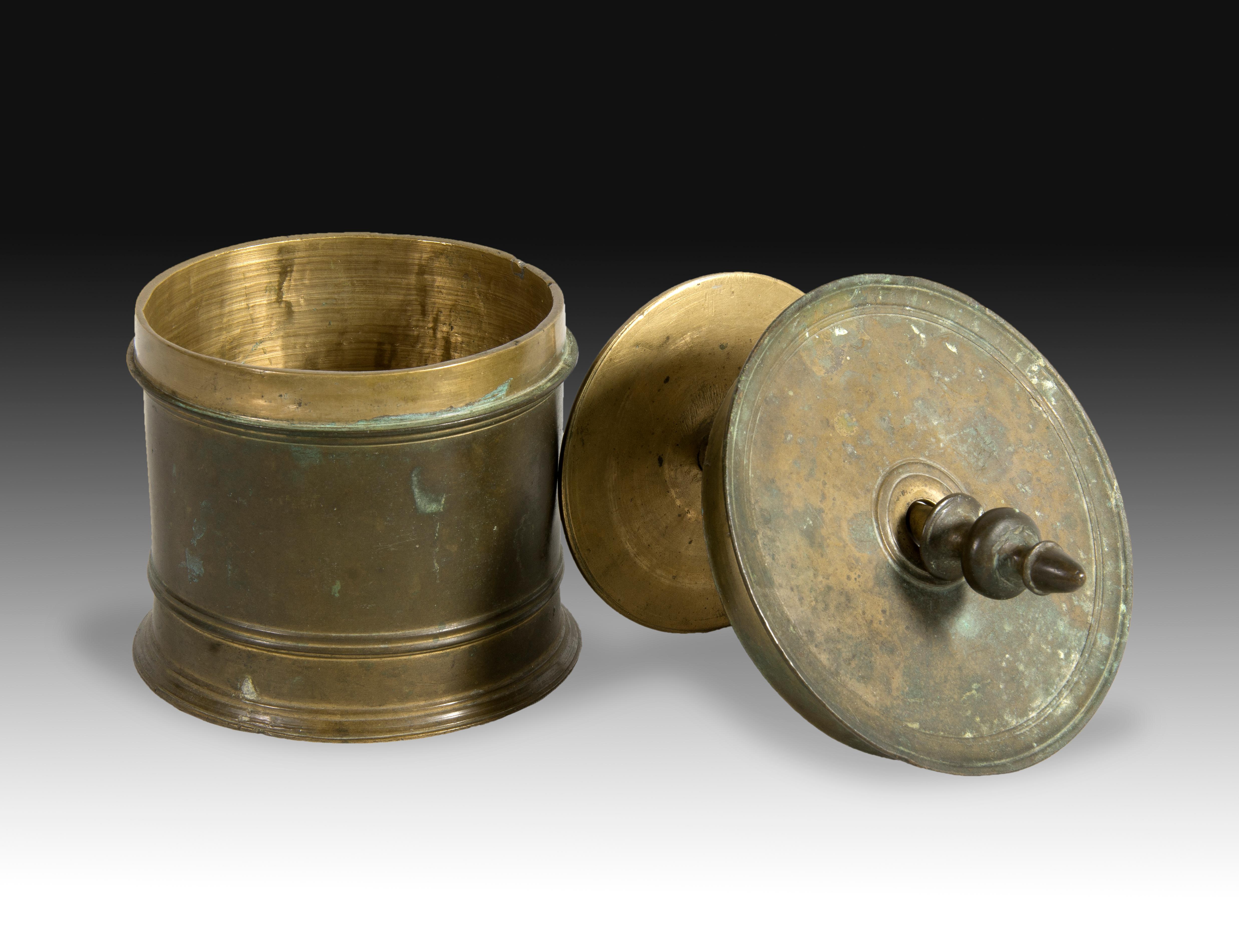 Hostiary. Bronze. 16th century.
 A circular, tubular bronze box with a finial lid, to which a piece of tubing is attached, forming a press for the interior of the case. It features a series of thin bands on the exterior for decoration, in addition