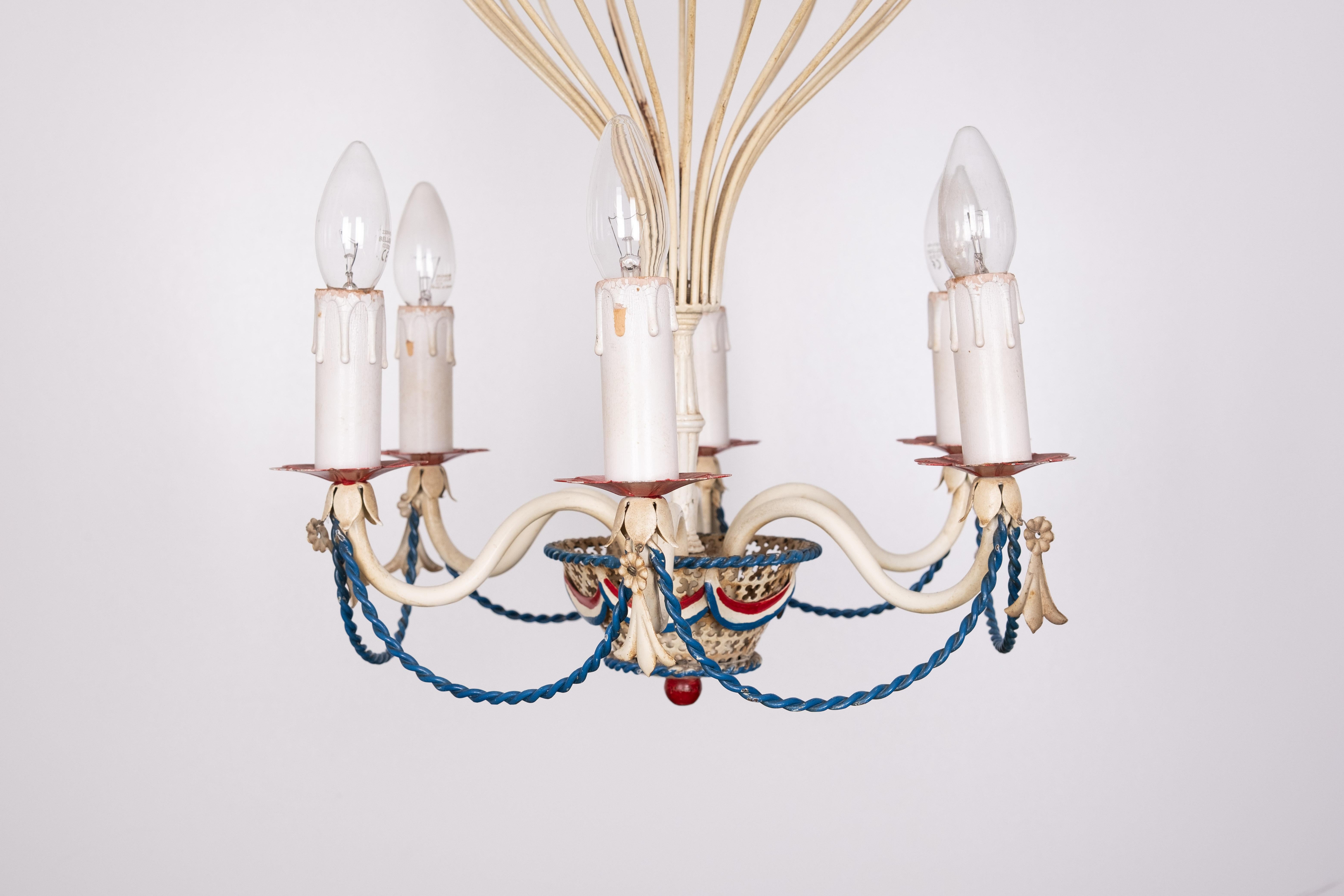 French metal frame Chandelier in the shape of an open work hot air balloon with six candle stye lights  Original off-white paint on metal, hand painted French flag with red, white and blue 
Comes with 6 matching shades .Small E14 bulbs needed .
 