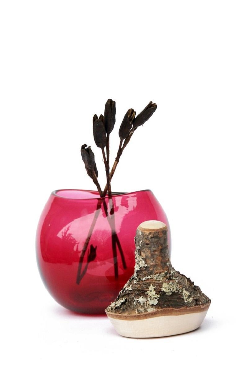 Hot pink branch bowl II, Pia Wüstenberg.
Dimensions: D 16-18 x H 20.
Materials: glass, wood.
Available in other colors.

A playful jar, with a lid made from a branch stub following the curvature of the glass. Branch bowls are blown without a