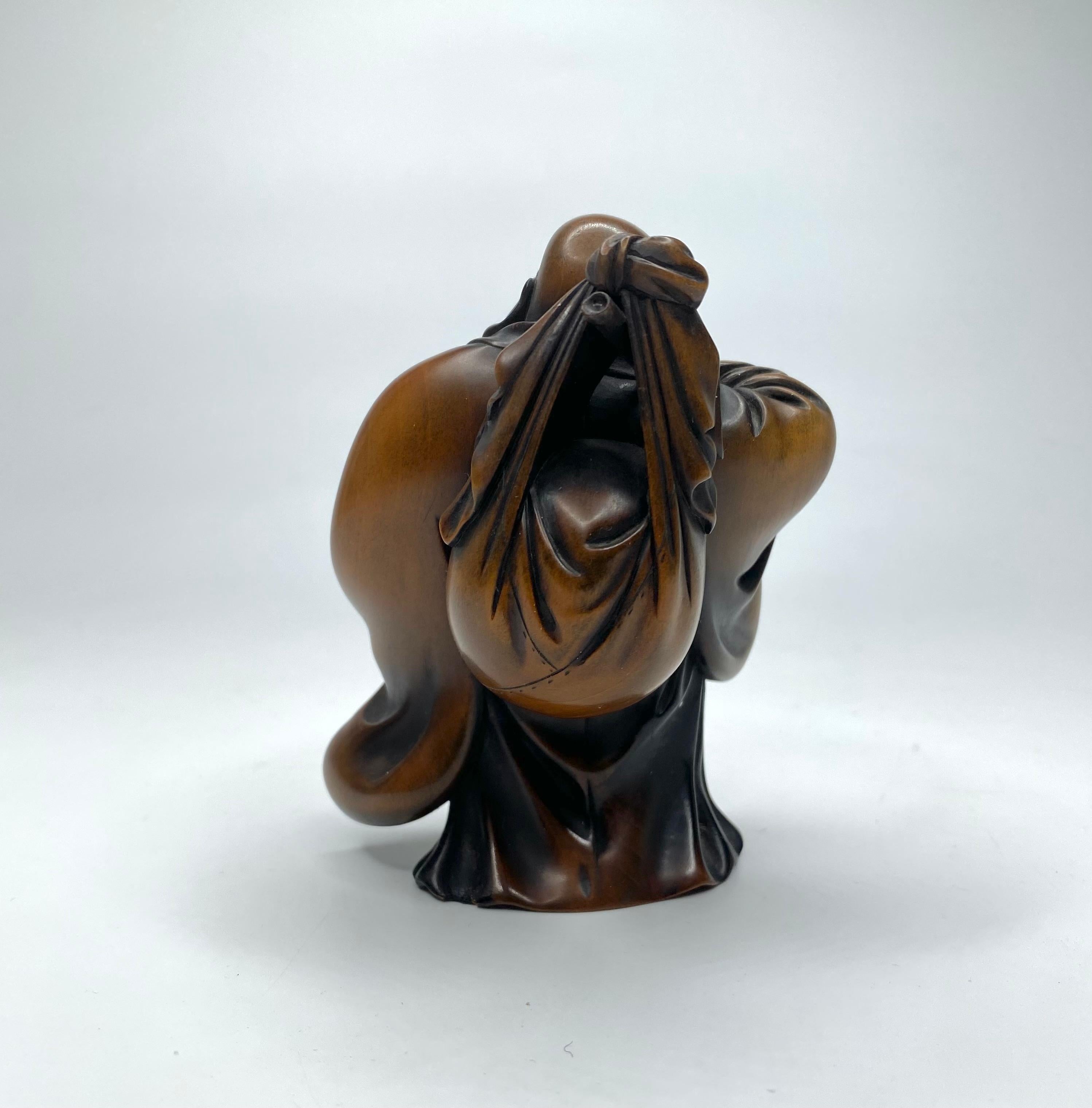 Japanese Hotei, a carved boxwood okimono, signed, Meiji Period.