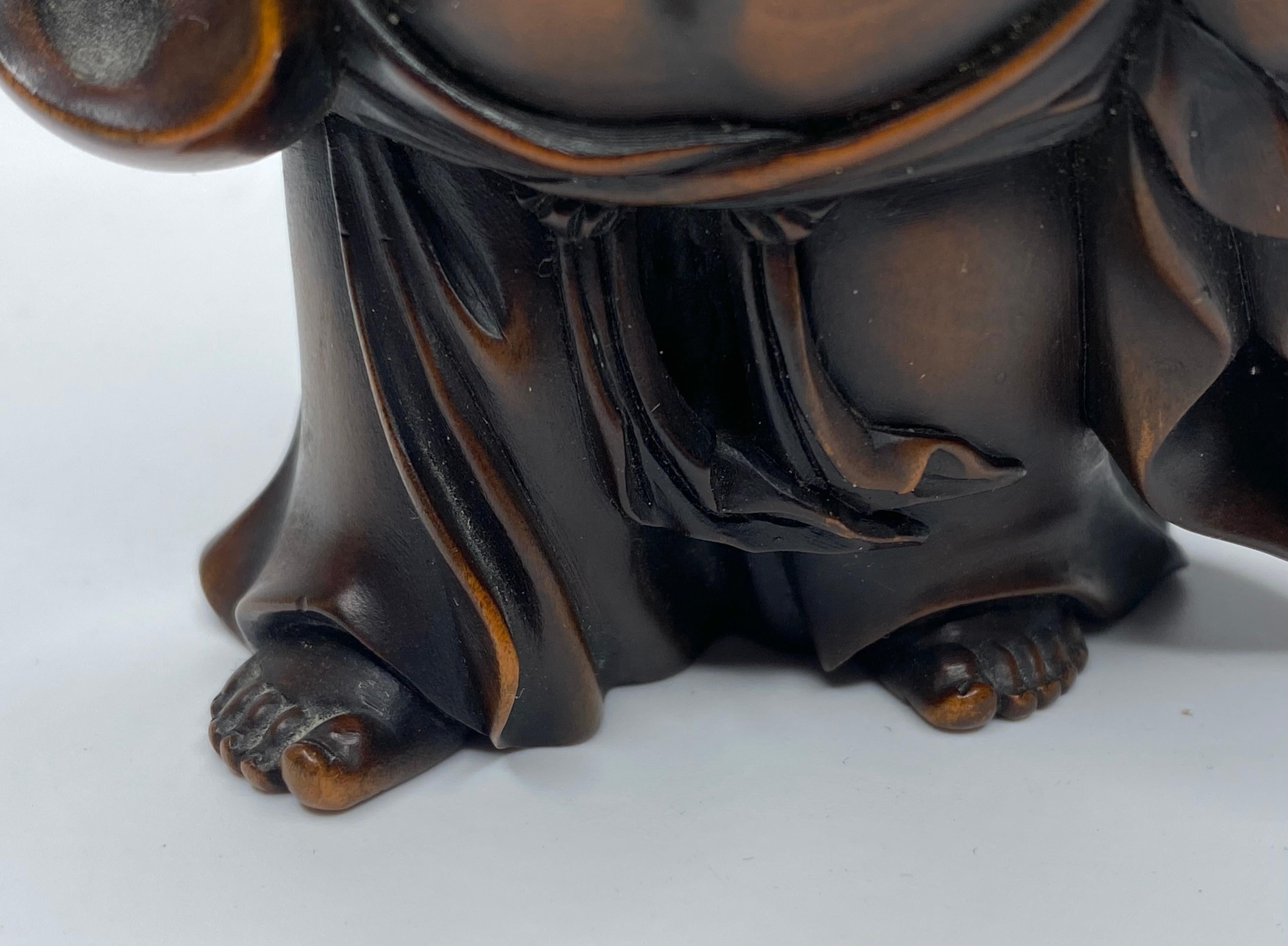 Hotei, a carved boxwood okimono, signed, Meiji Period. 1