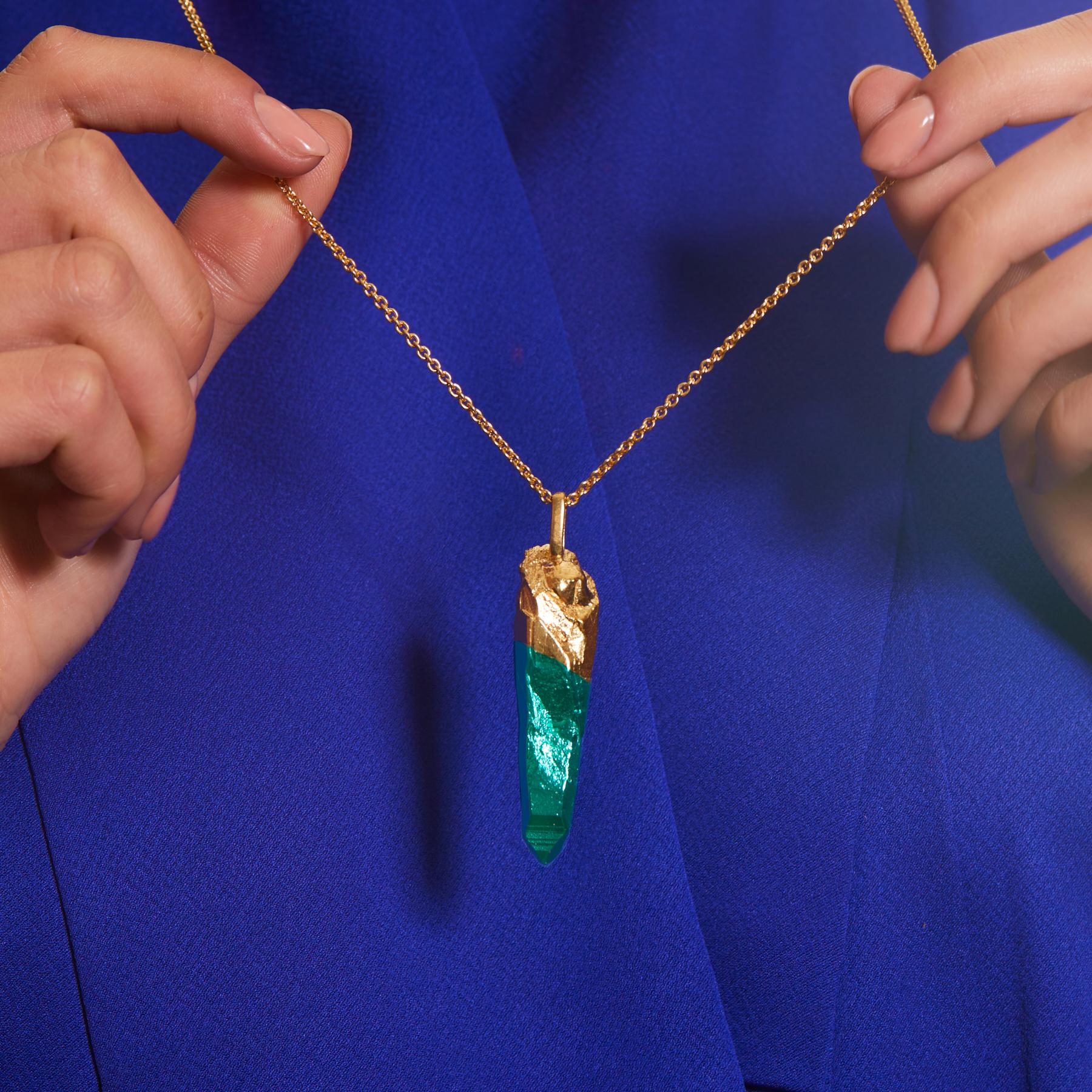 Collana con bacchetta HotRocks Alchemy in vermeil giallo 18ct Fairmined Gold con punta rivestita in ceramica verde acqua. La forma del ciondolo riproduce una bacchetta di quarzo naturale, creata attraverso il processo di fusione a cera persa, che