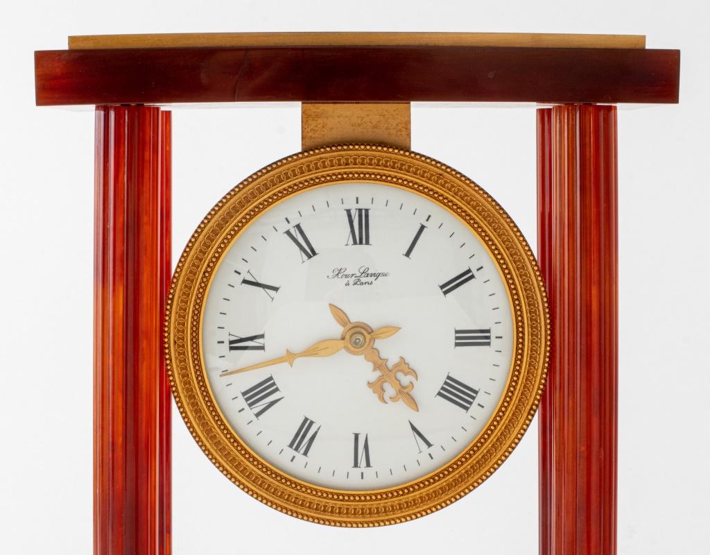 Horloge de cheminée Lavigne Paris, composée de quatre colonnes cannelées en résine ambrée reposant sur une base en résine et laiton, marquée.

Dimensions : 11