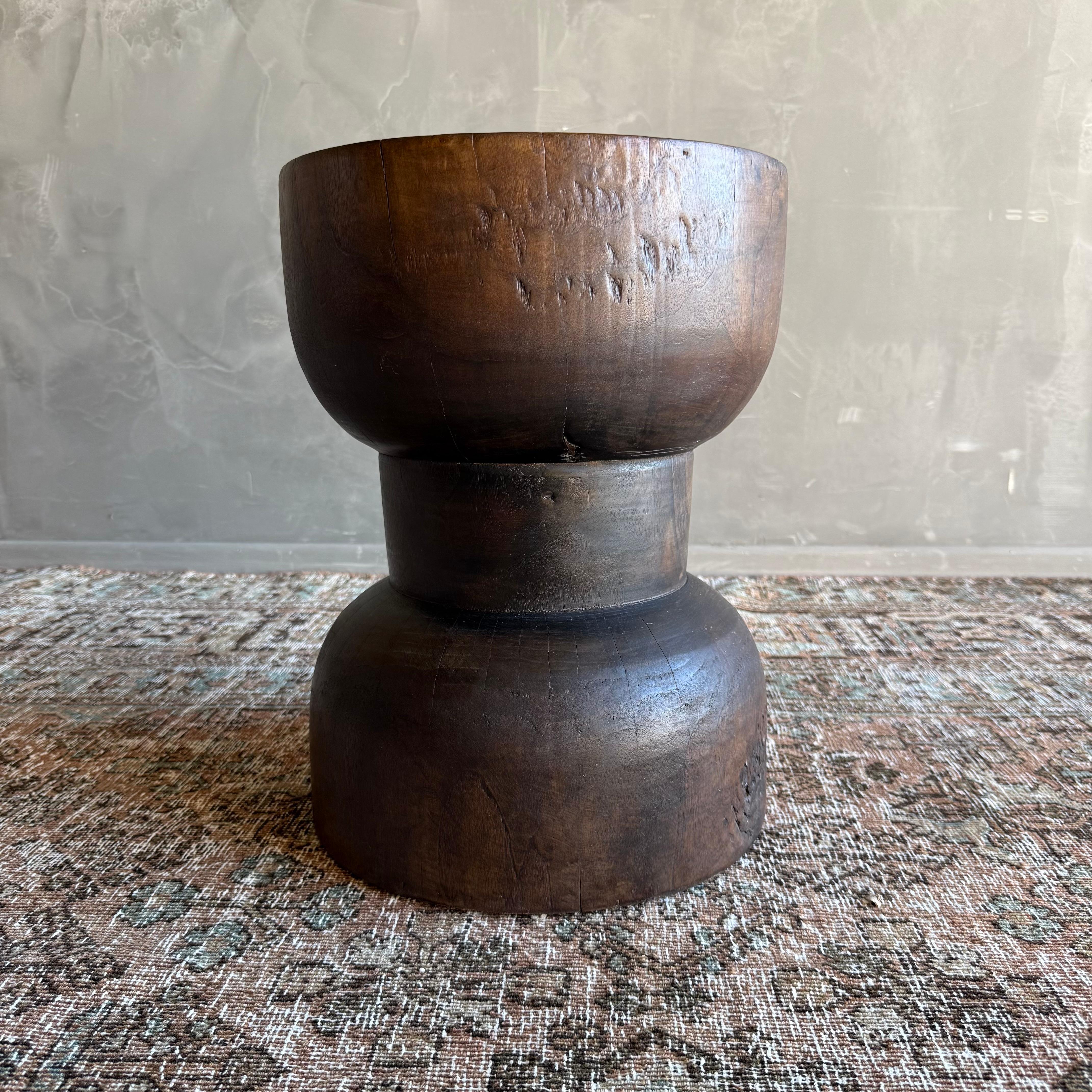 This stunning reclaimed wood stump table, crafted from rich walnut, features a unique hourglass shape that adds an artistic flair to any space. Its organic form showcases the natural beauty of the wood, with varying tones of deep browns and warm