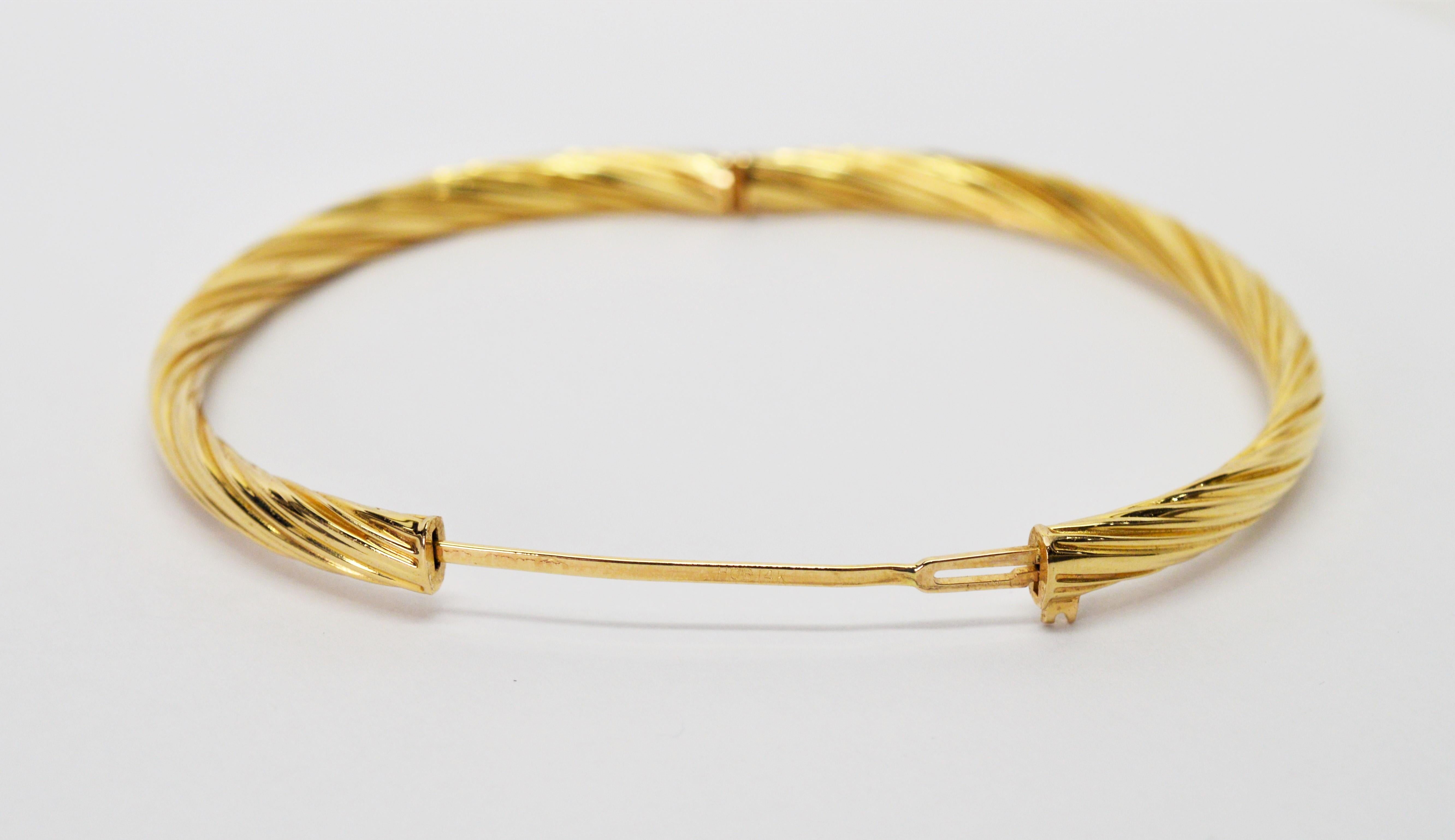 In fourteen carat 14K yellow gold, this HOB signed bangle bracelet has a versatile and classic twist design. Fitted with a hinge and plunger clasp, the bracelet's inside measurements are 2-1/4 x 2 inches. (Linear measurement 7 inches).  In gift box.