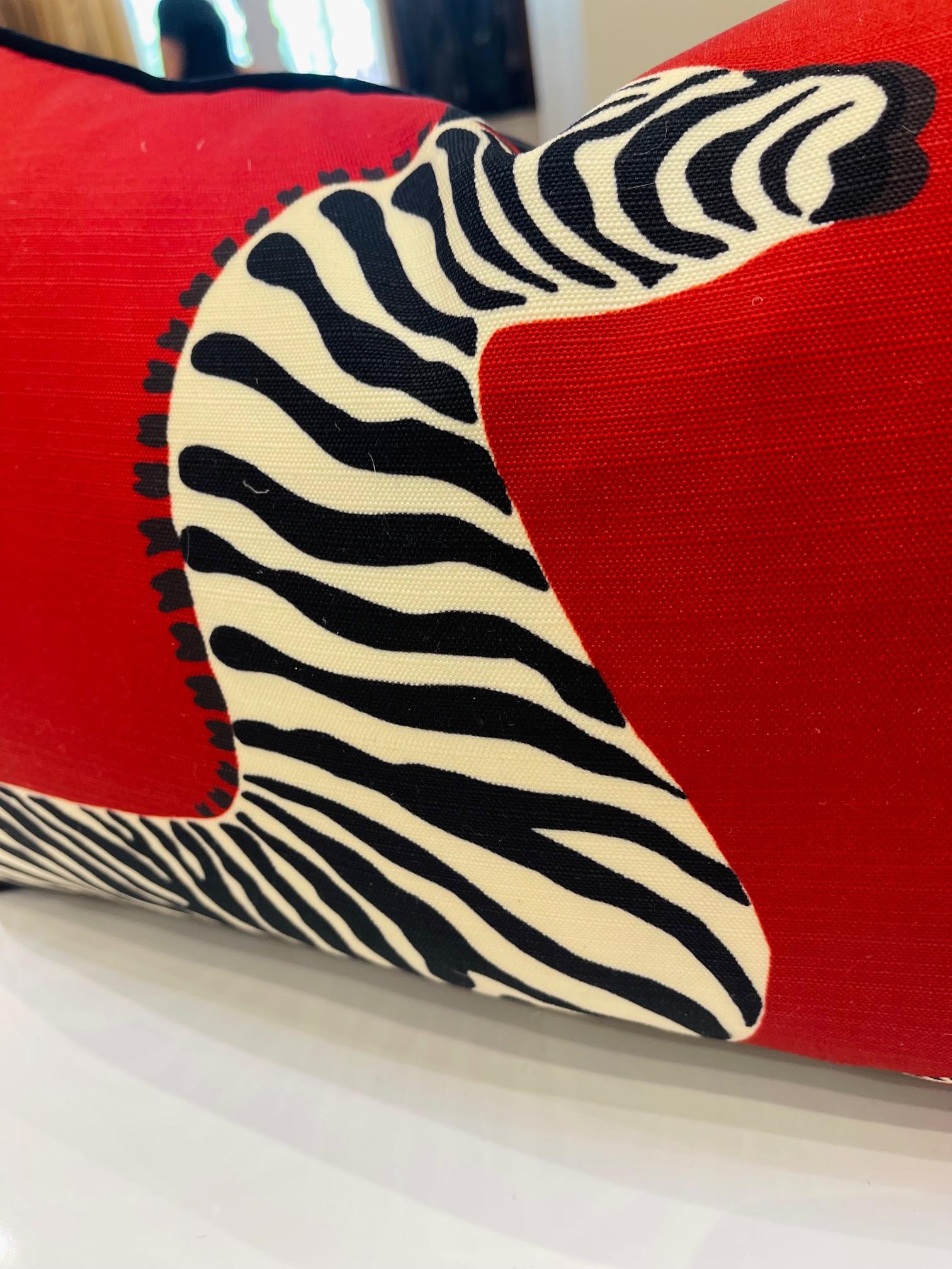 This luxury plush pillow is a product of the Art by Gomez atelier. The front is fitted with a rich, vibrant red that supports a pattern with galloping zebras. The fabric is from the archives of the luxurious House of Scalamandre. The back is a rich