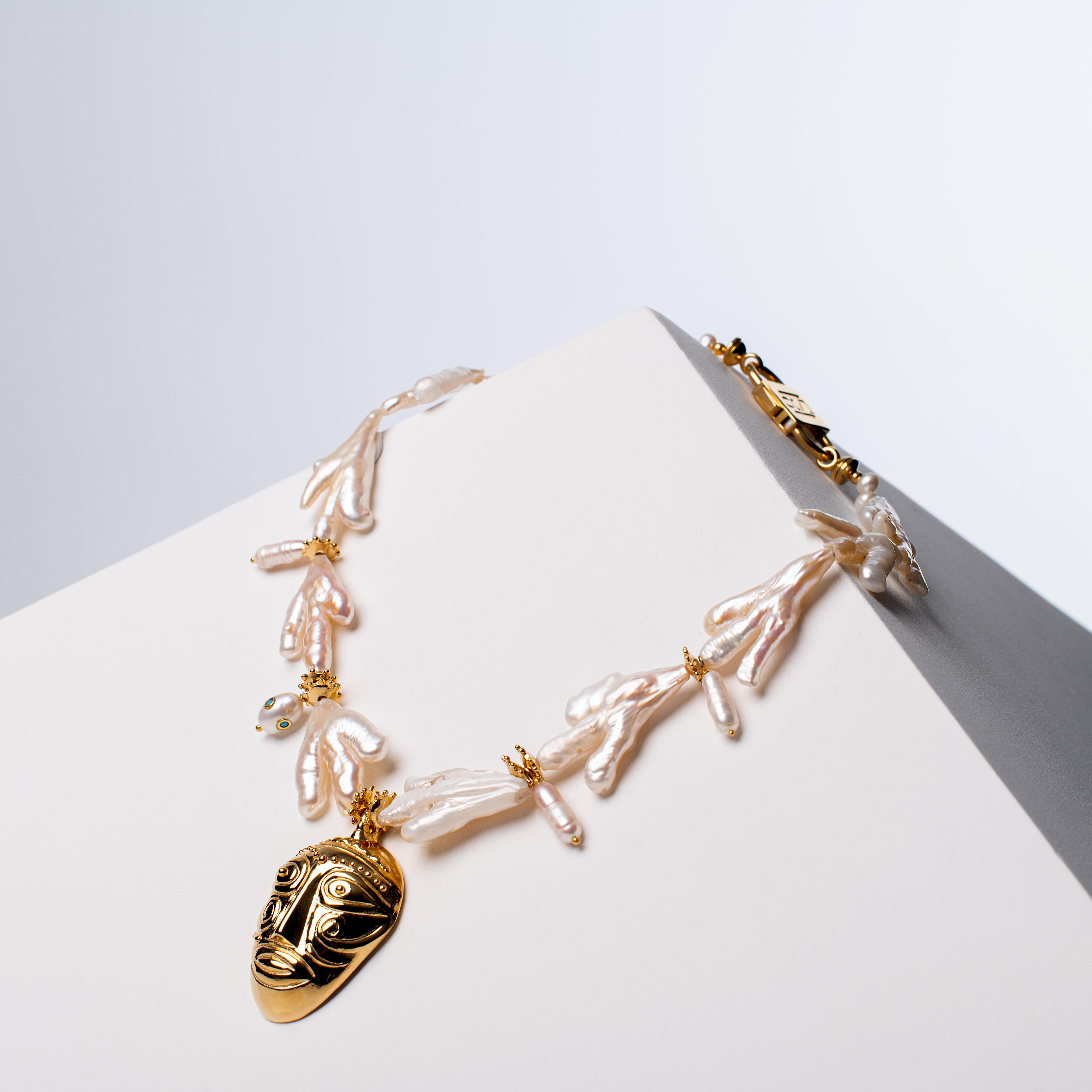 - Dieses Collier ist eine avantgardistische Kreation aus natürlichen Keshi-Perlen und einzigartigen Ornamenten, ergänzt durch die hauseigene afrikanische Maske, die mit 1 Mikron 24-karätigem Gold über 925er Sterlingsilber veredelt wurde, was sowohl
