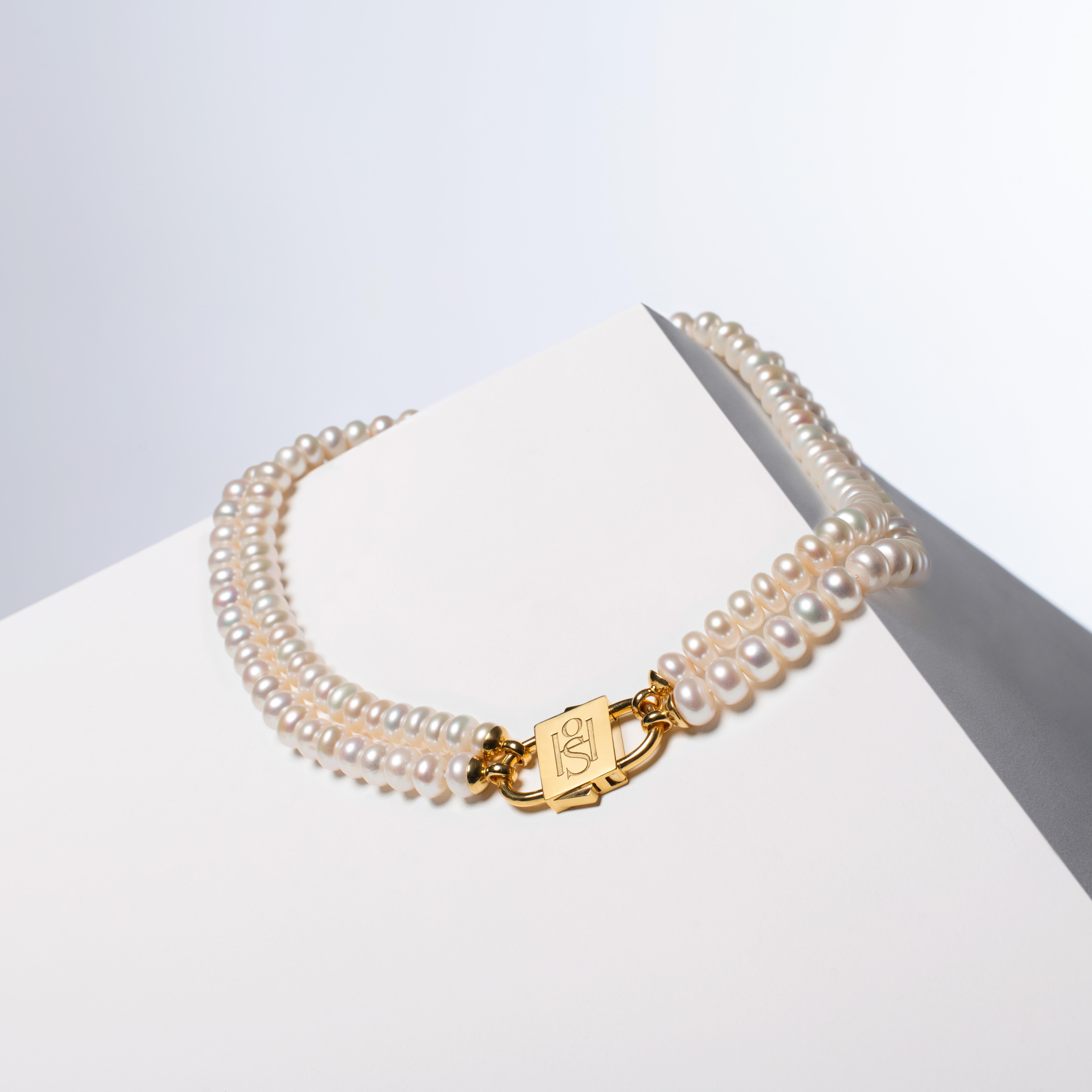 - Questa parure comprende due collane individuali, ognuna delle quali è impreziosita da perle a bottone bianche naturali ad alta lucentezza e da HoS Lock™ in argento sterling 925 riempito d'oro 24k da 1 micron, per offrire versatilità nello stile.
-