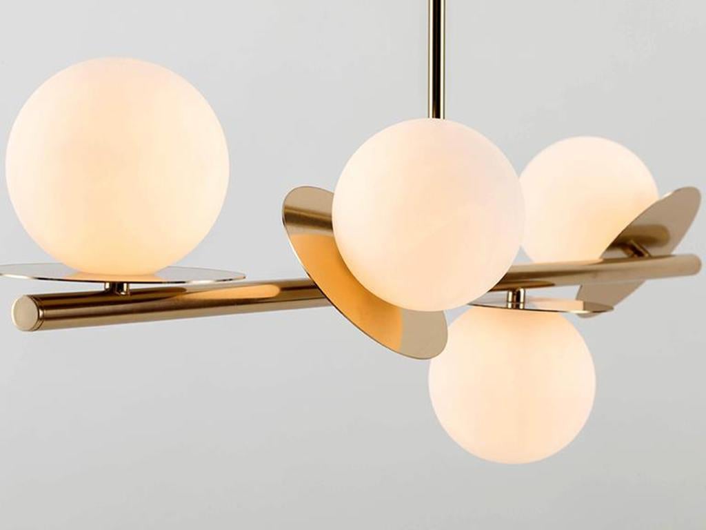 Esta moderna lámpara de techo se adapta a techos altos y bajos. El tallo metálico alargado suspende cuatro pantallas de cristal opalino montadas en disco, que difunden un cálido resplandor iluminador. Ideal para un comedor o un salón. Rico y