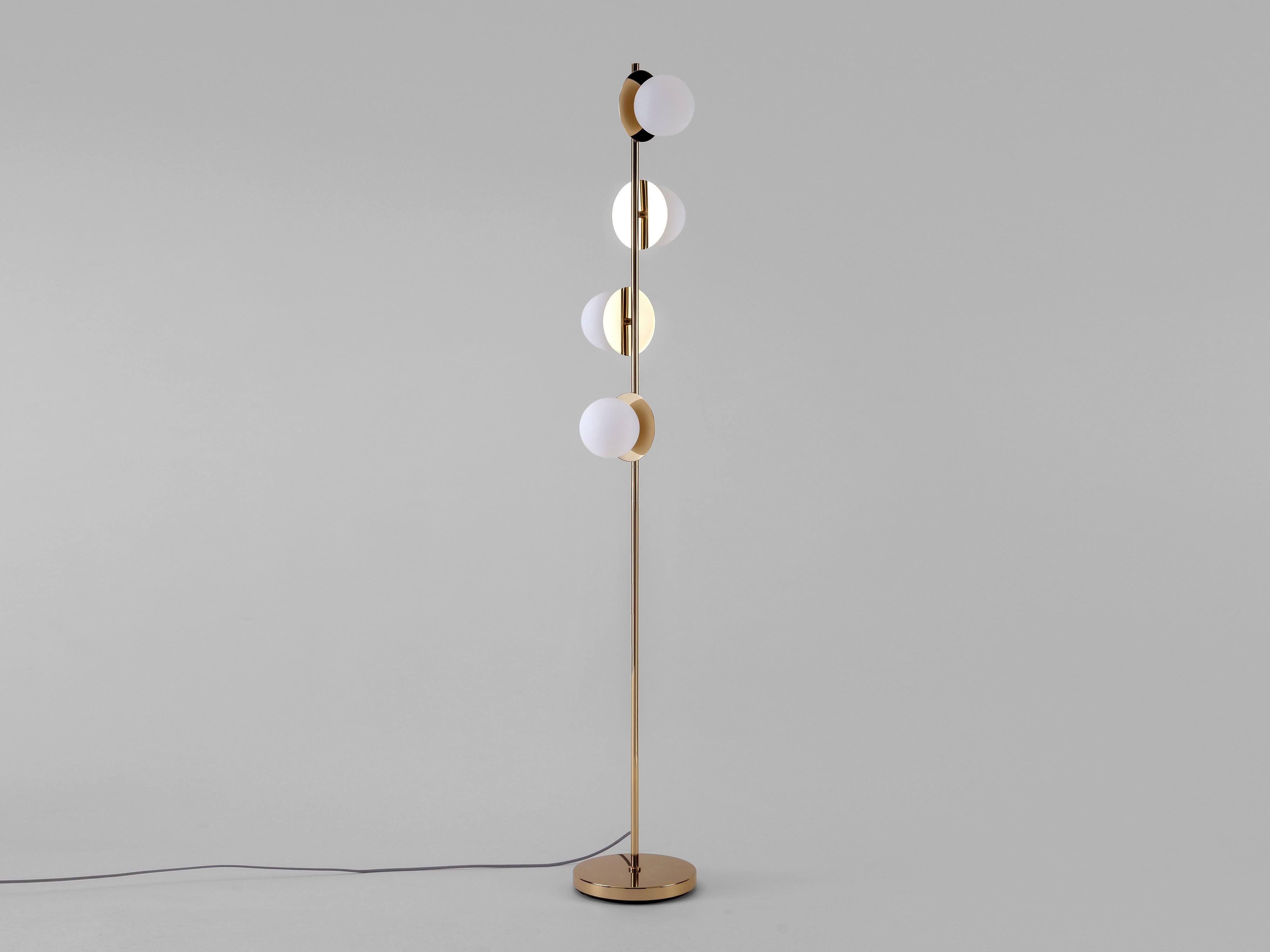 A contemporary floor lamp to transform your space. Sculptural shapes and soft light come together to create this beautiful and elegant brass standing floor lamp. Four opal shades sit on reflective brass disks, spreading a warm bright and