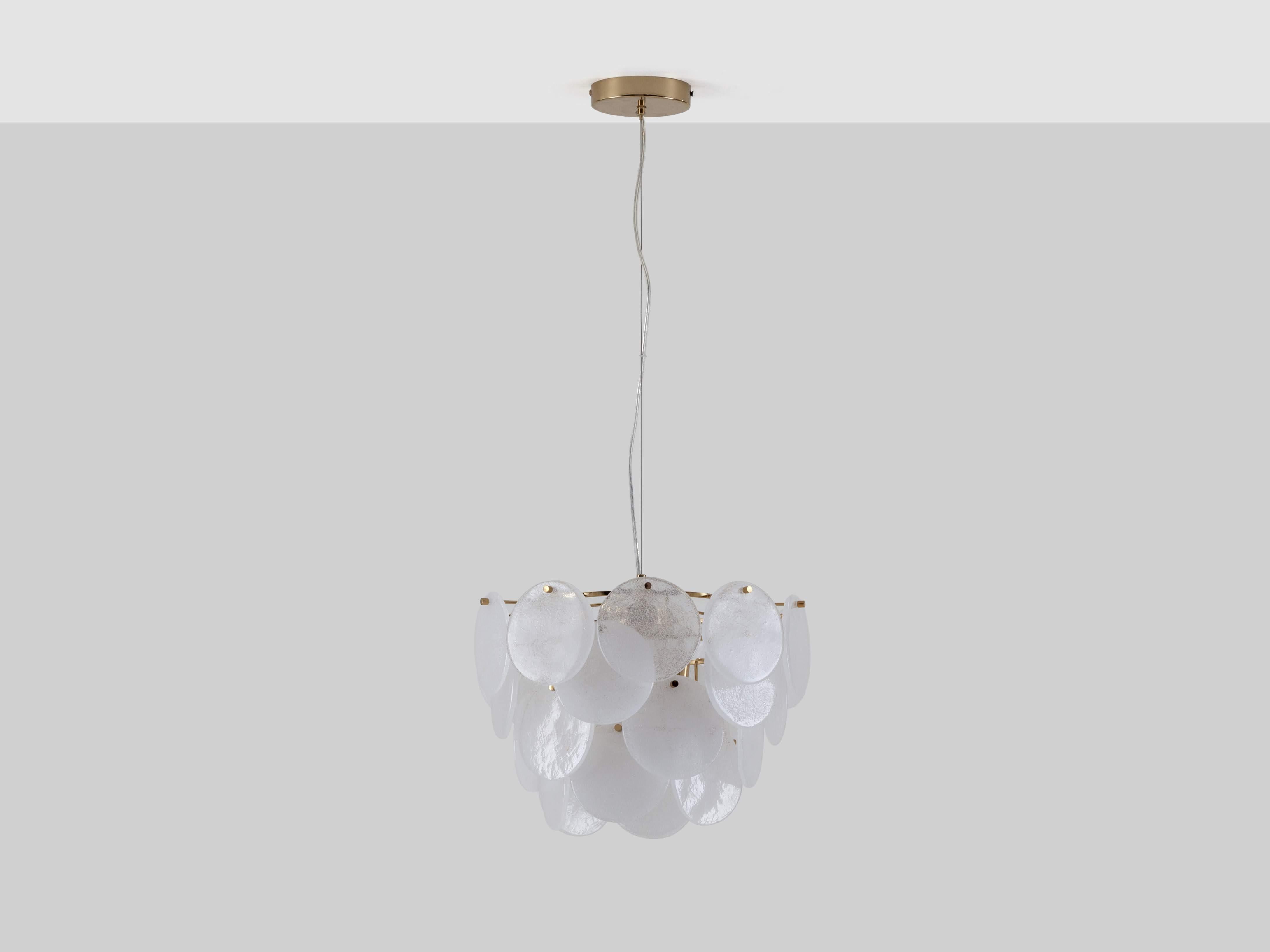 An elegant chandelier, perfect even for smaller rooms, this piece has become an icon in the houseof collection. Suspended on a brass frame, the glass disks delicately refract light across the room, creating a warm ambient glow. Ideal for styling in
