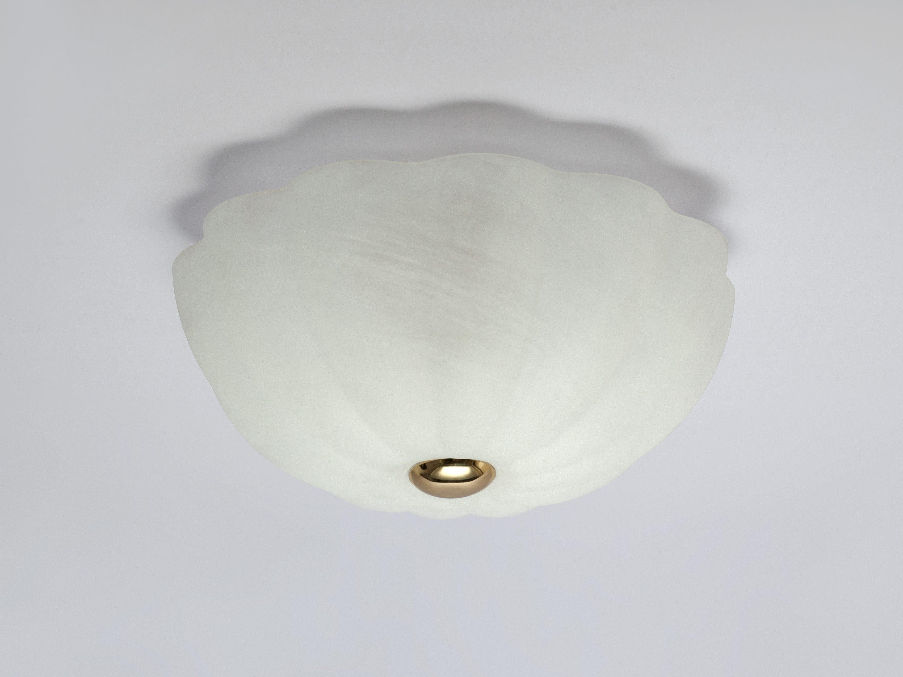 This low profile flush fit ceiling light is perfect for low ceilings or as a striking sculptural focal point. The flower shaped opal glass shade diffuses a warm illuminating glow. Rich and opulent, the brass detail add a luxurious finish to the soft