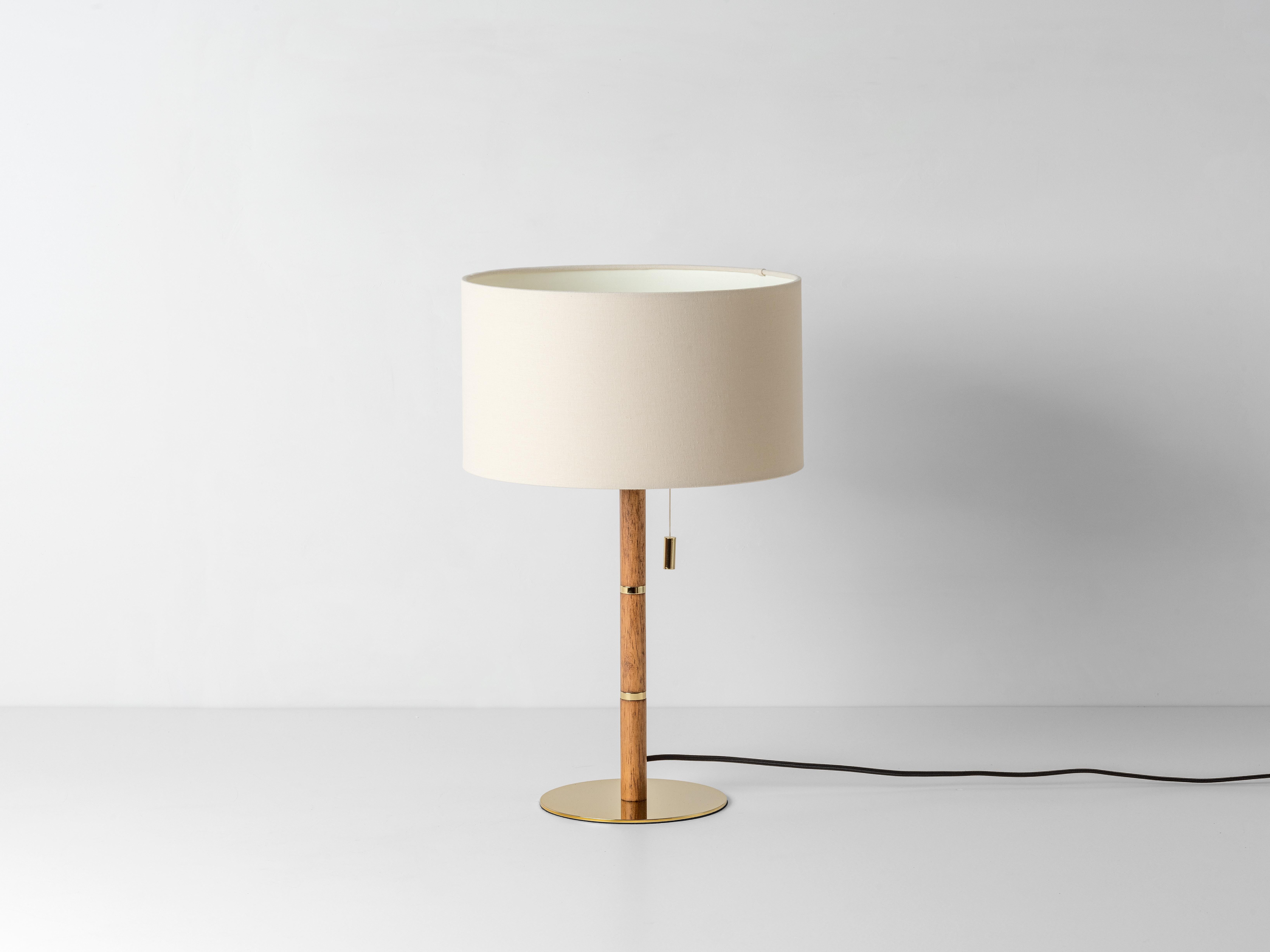 Please note this product is on pre order.

This perfectly formed table lamp is the ideal reading companion, with considered details such as a pull switch and responsibly sourced wood. The contrasting textures of slubby linen, smooth brass and