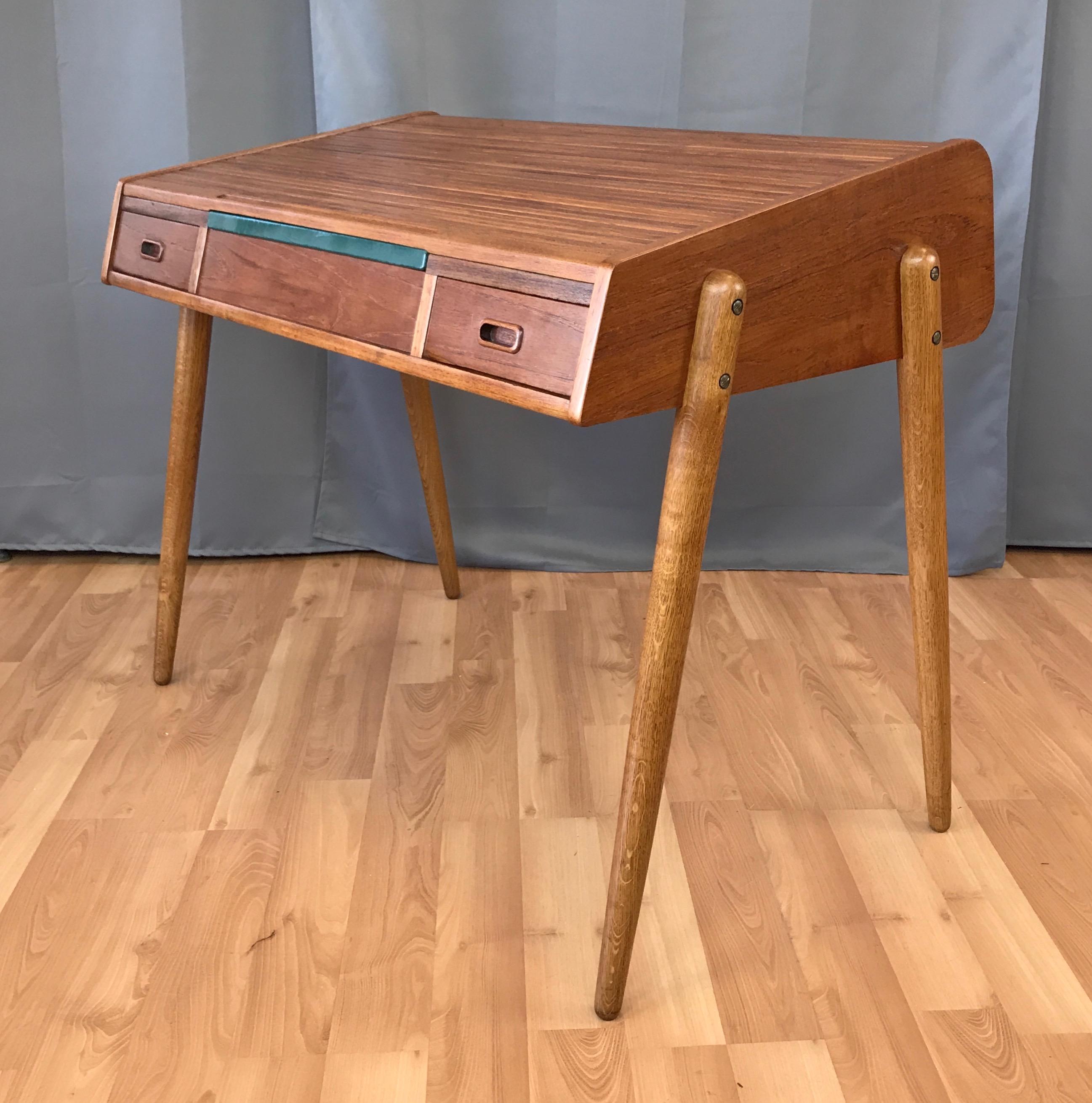 A rare Scandinavian Modern teak and oak roll top desk with solid core pine construction by Arne Hovmand-Olsen for Mogens Kold Møbelfabrik.

Sleek teak cabinet with great lines on tapered oak legs that give it a spry, light on its feet appearance.
