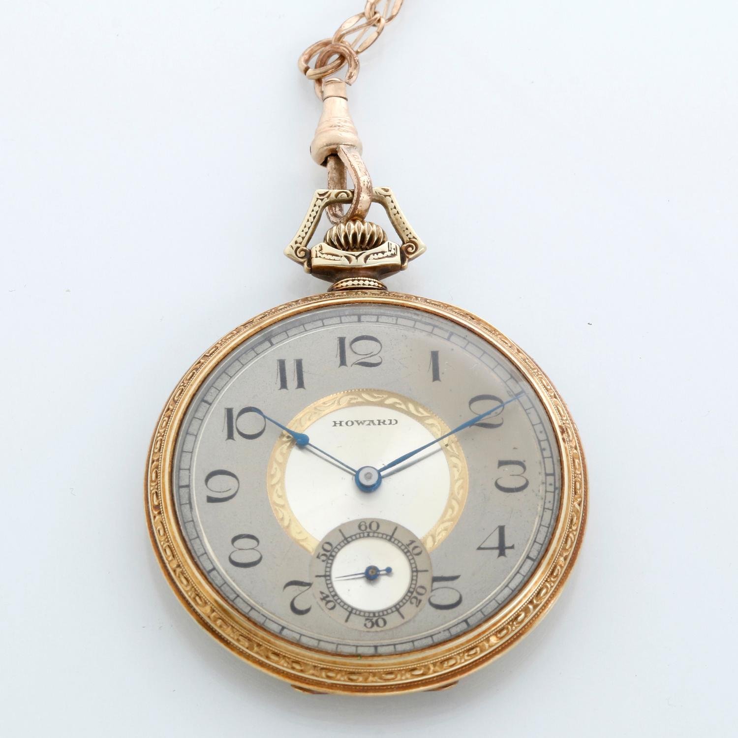 Howard 14K Yellow Gold Pocket Watch with Gold Filled Chain - Manual winding; 19 jewels . 14K  Yellow gold with ornate engraving on the back ( 44 mm). 2 tone silver dial with gold inner circle.  Arabic numerals, sub dial at 6 o'clock. Pre-owned with