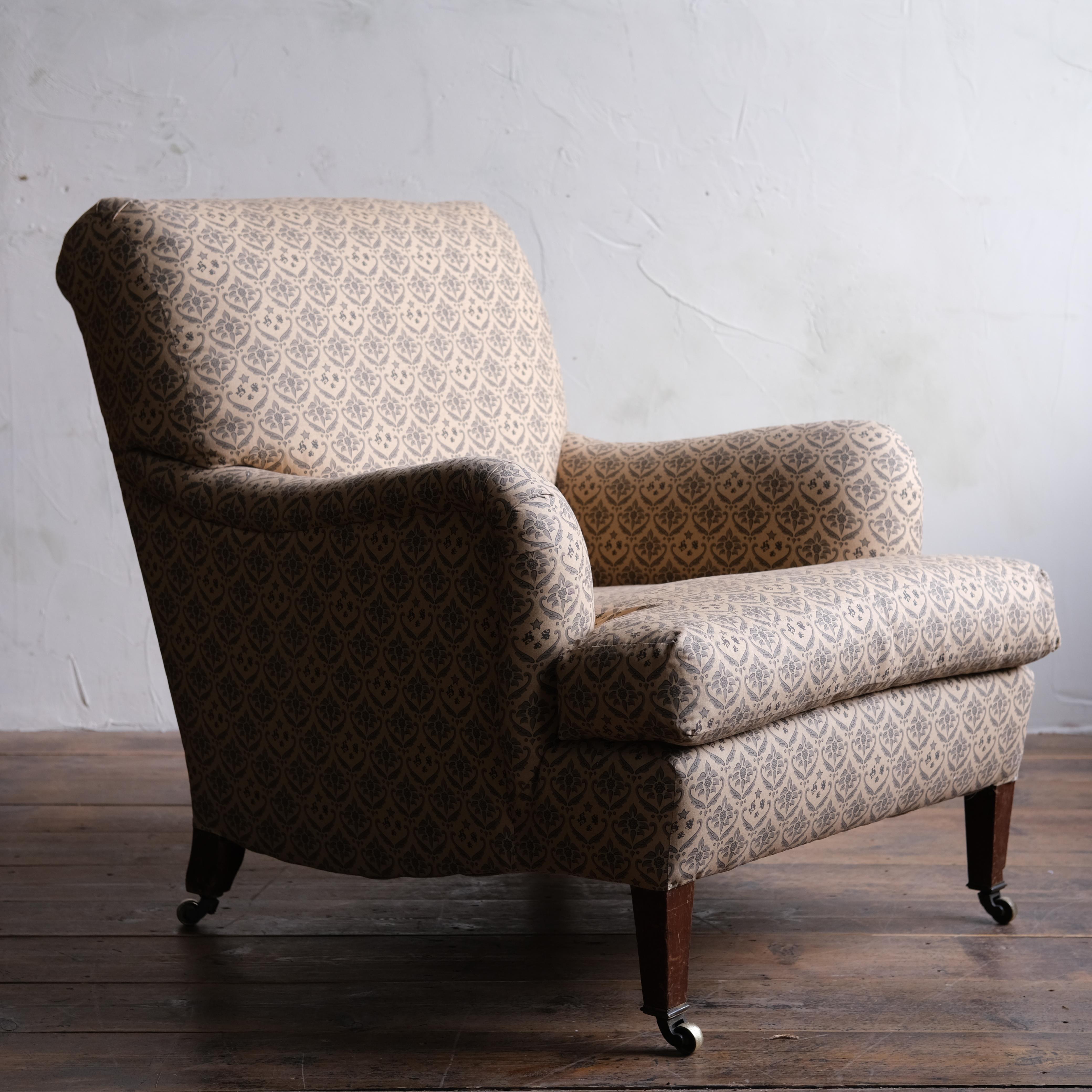 A Howard and sons Bridgewater armchair raised on square tapered walnut legs all with the original brass H&S stamped casters. The back left leg stamped with both serial number and the maker's mark.

Upholstered in H&S branded cotton under ticking