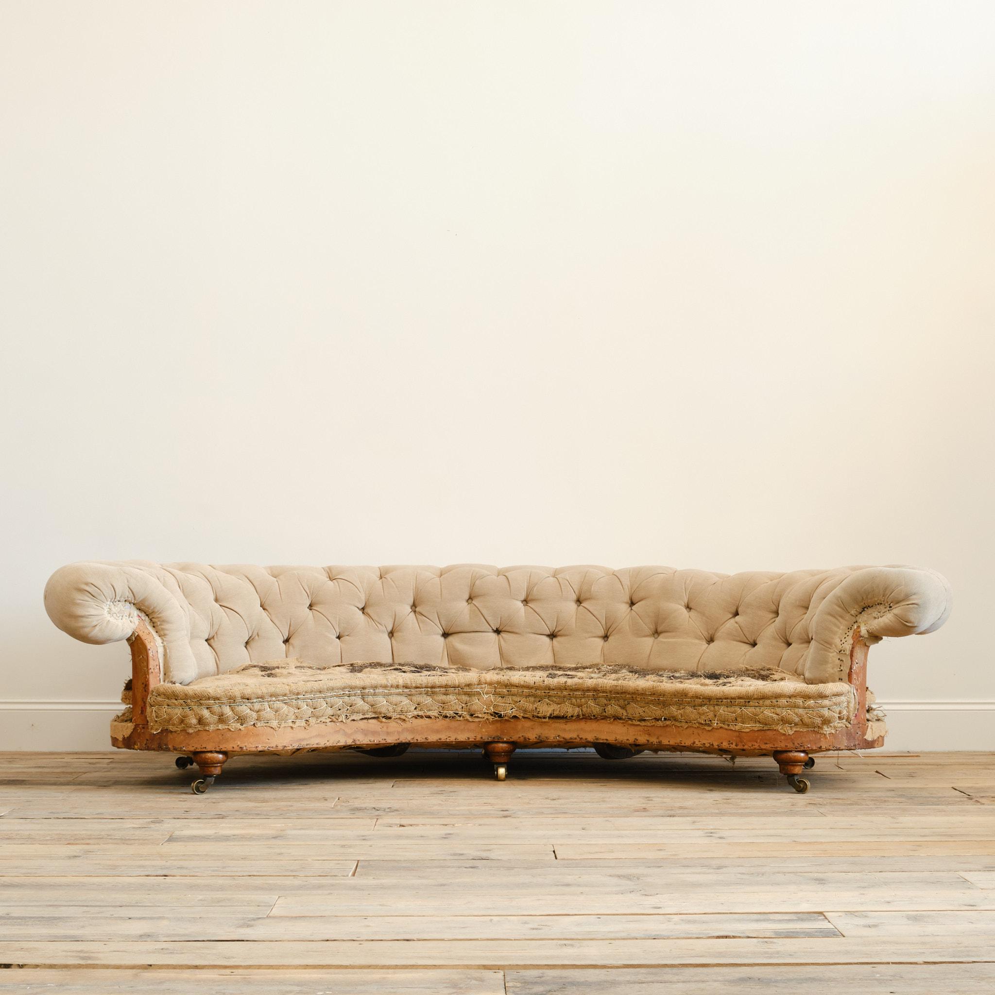 A huge 19th century 'Crescent' shaped country house chesterfield sofa by Howard & Sons - London c1860. Raised on 6 short walnut legs with 3 turned front legs and 3 splayed rear legs. The back middle leg stamped with the the serial number 13064-6373