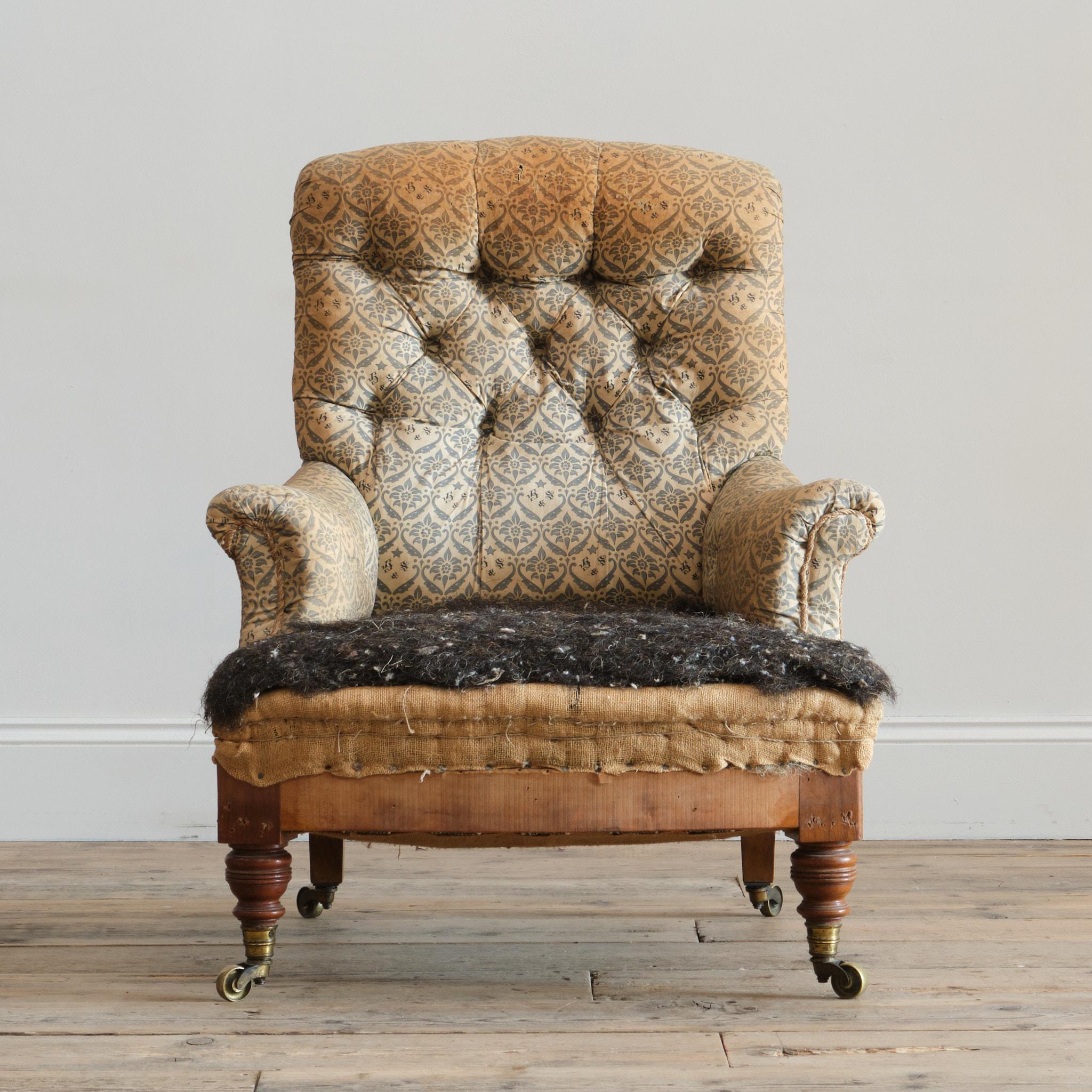 A shapely Howard & Sons 'Hammond' model armchair. Raised on Howards unique ring turned walnut front legs and splayed rear legs, all with the original H&S stamped casters. The chair retains its original upholstery and fillings with the seat being