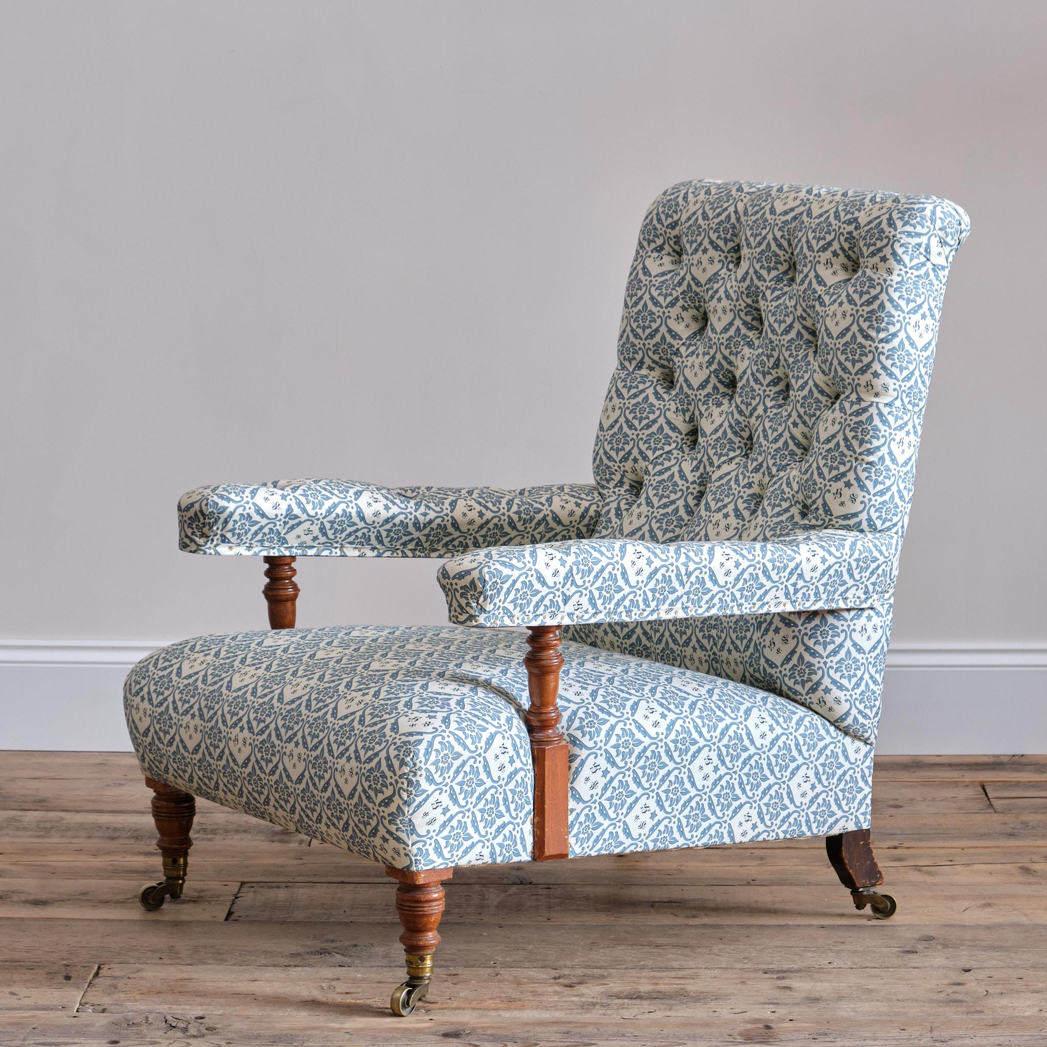 A Howard & Sons deep seated open armchair raised on walnut turned front legs and arm supports. Splayed rear legs with the back left leg number stamped and bearing the makers mark. All legs with the original Stamped H&S casters.

Newly upholstered in
