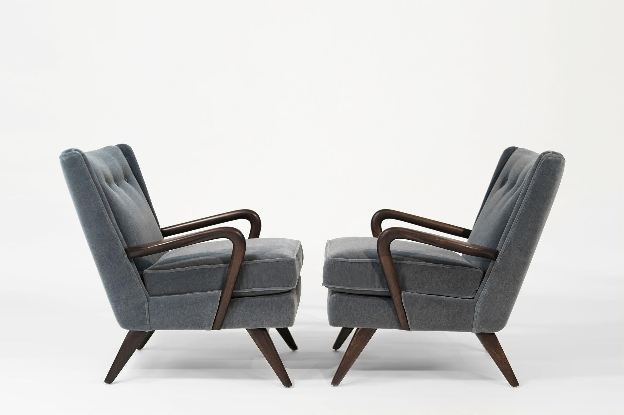 These Howard Keith “Bambino” lounge chairs epitomize HK Furniture’s legacy and mid-century English design. Crafted in the late 1940s-50s from solid beech, it has been fully restored in a rich dark tone and re-upholstered in gray-blue mohair. With