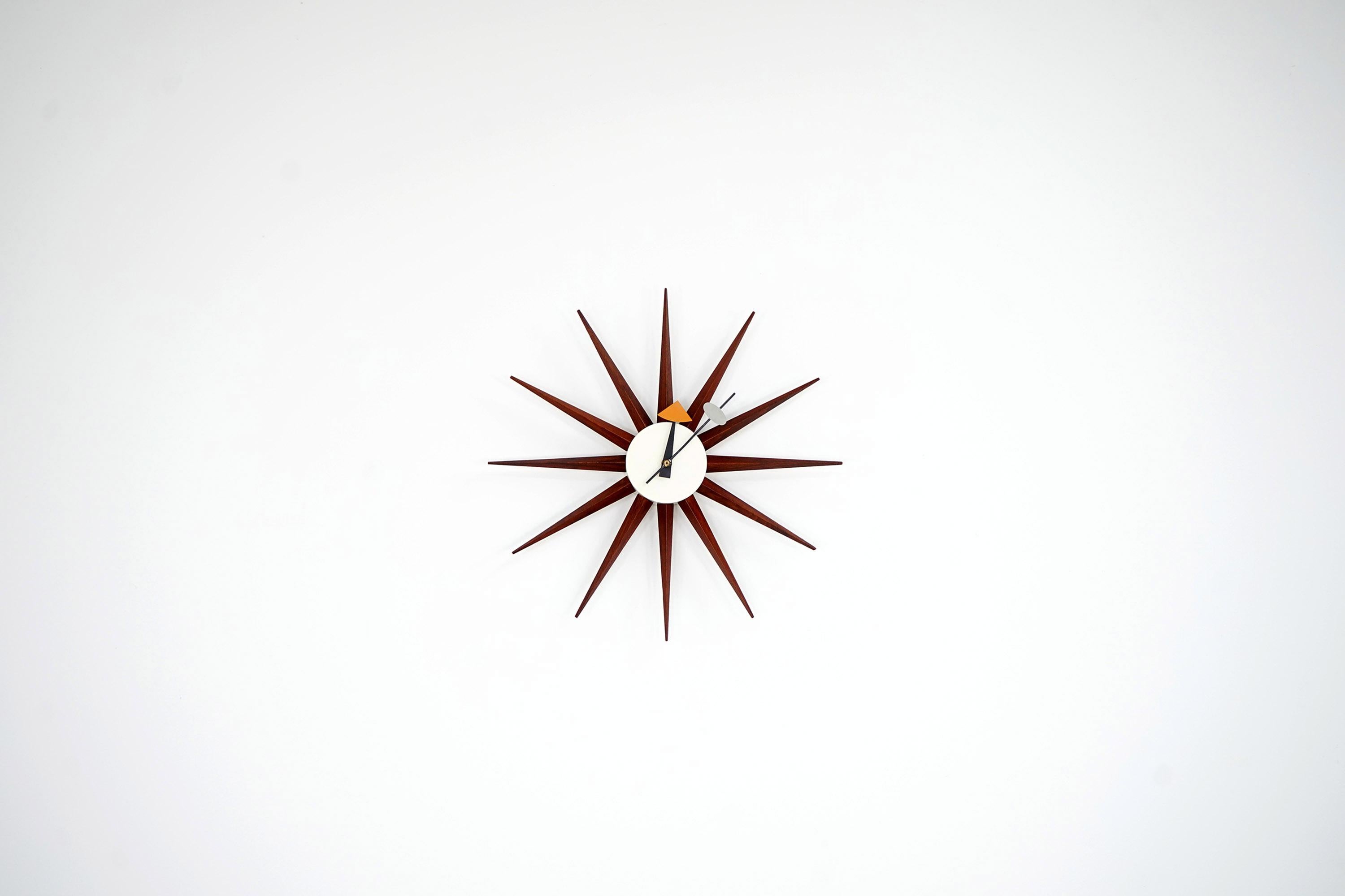 Diese schöne Howard Miller Uhr stammt aus den 1950er Jahren. Das Design stammt von George Nelson. Das Stück wurde von den Gebrüdern Fehlbaum in der Schweiz hergestellt. Das Gehäuse der Uhr ist aus Metall gefertigt. Die Spitzen sind aus Teakholz