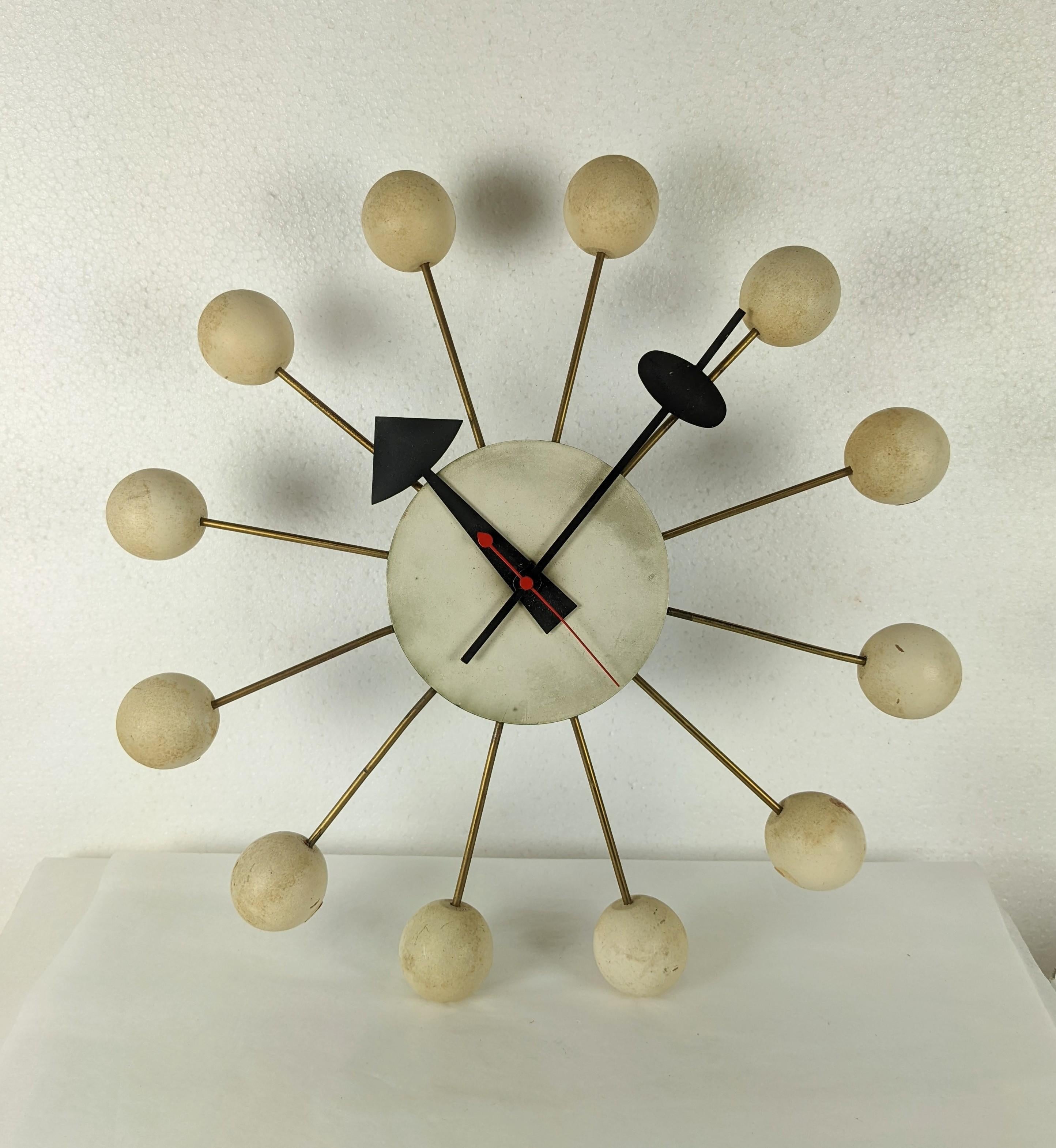 Iconic and classic Howard Miller ball clock from the 1950's by George Nelson. Wonderful Atomic style with a central clock motif with 50's style arms. Twelve brass spokes have painted cream wood balls with matching black hour and minute hands