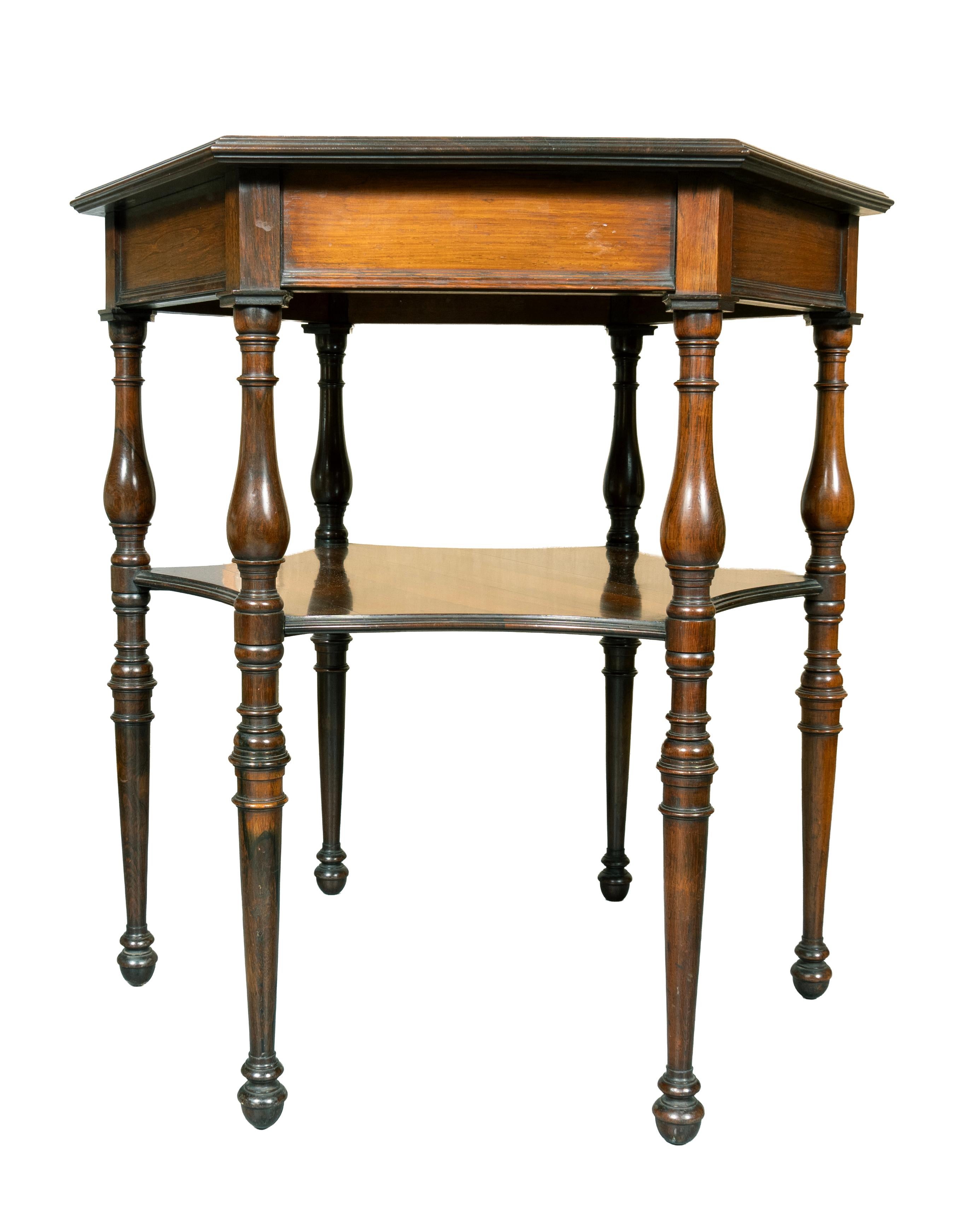 Con tablero octogonal apoyado en seis patas torneadas con estante inferior. Terminando en patas torneadas y pies en forma de bellota. Etiqueta de Howard and Sons, Londres, debajo de la parte superior. Howard and Sons recibió varias órdenes reales y