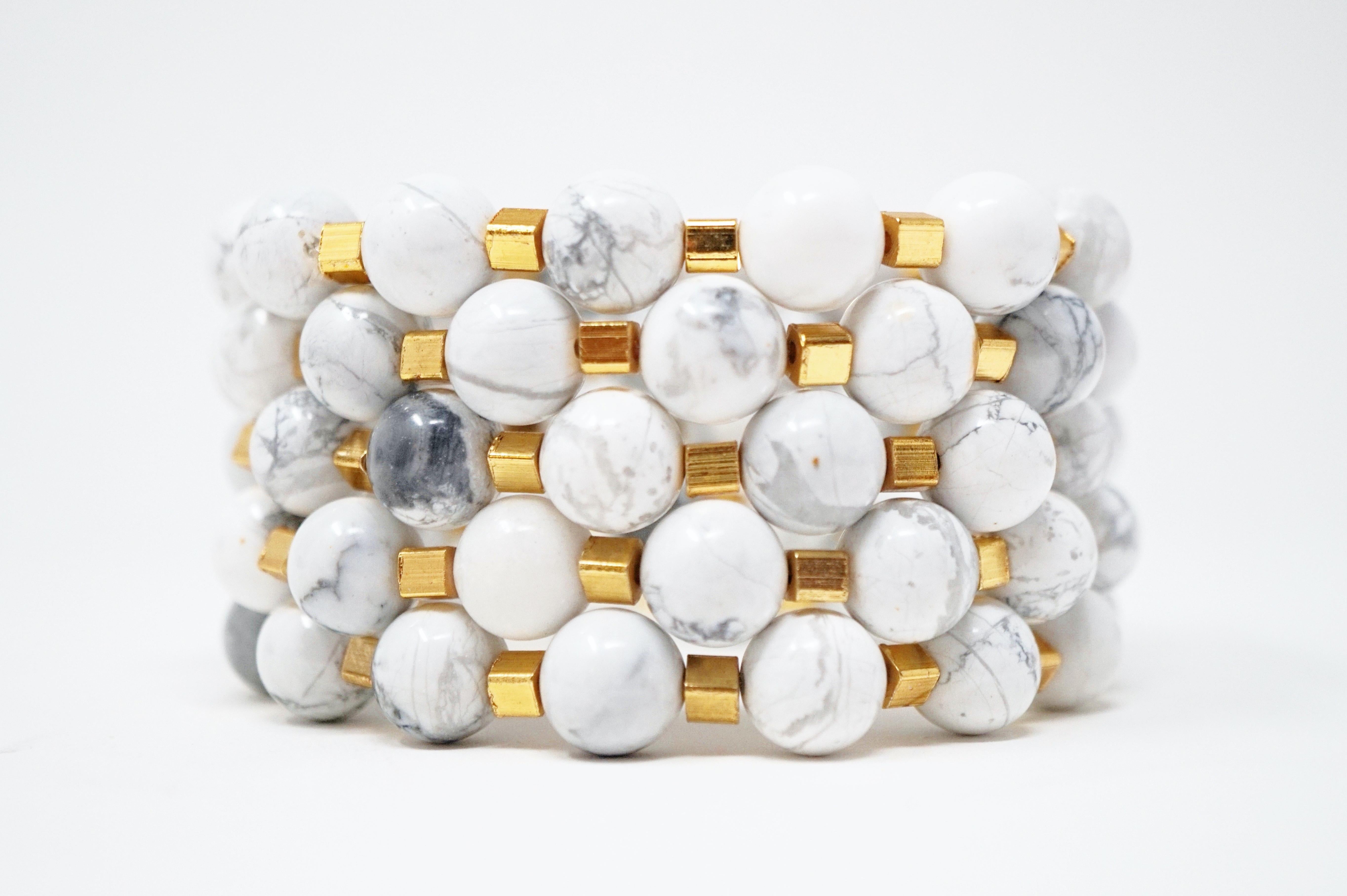 Dieses wunderschöne Armband aus natürlichem Howlite-Edelstein mit vergoldeten Akzenten besteht aus fünf einzelnen Armbändern, die einzeln getragen oder für einen gewagten Look übereinander gelegt werden können. Wenn sie gestapelt werden, schmiegen
