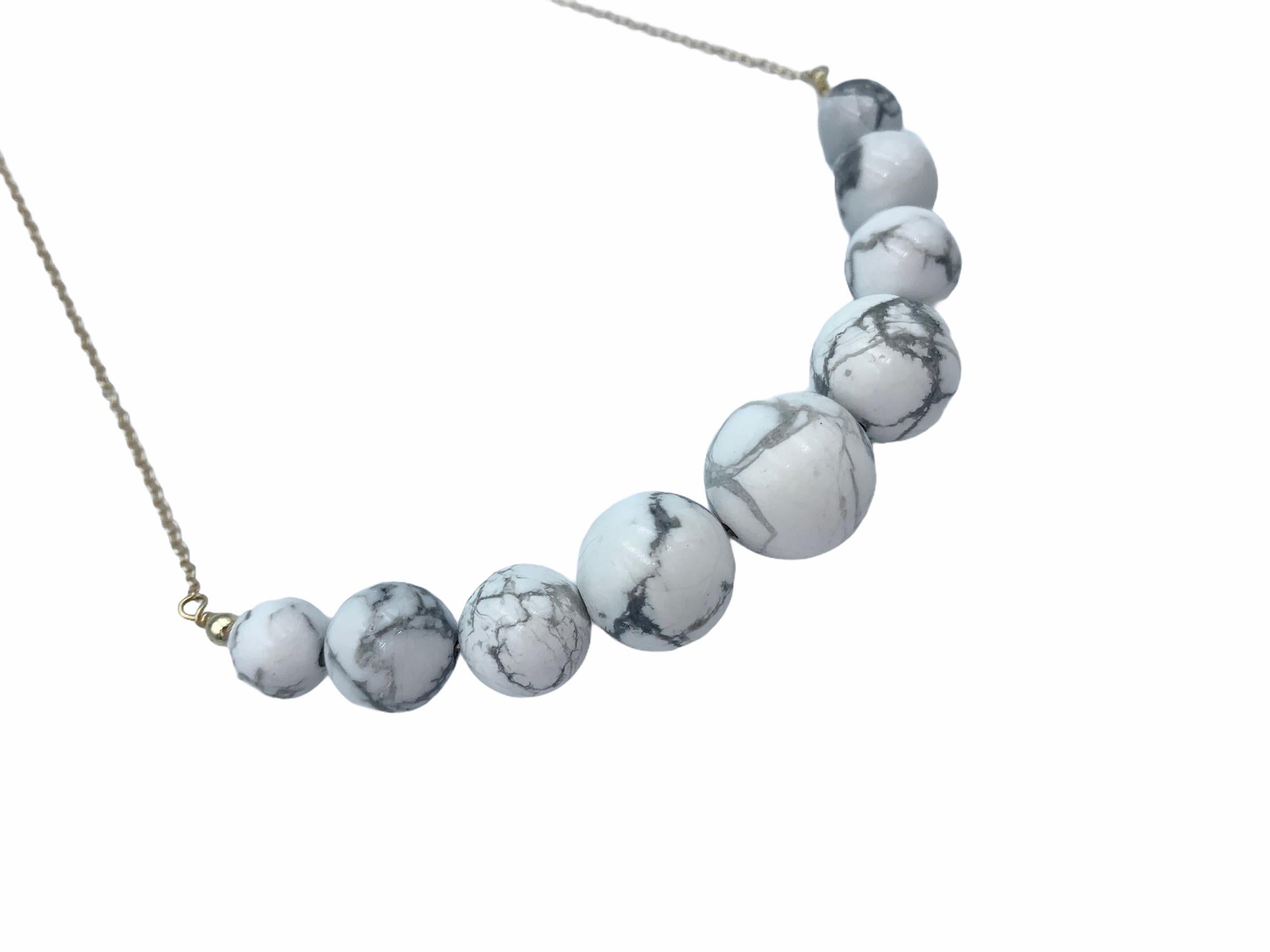 Hand made using 14 carat Yellow Gold, the suspended Howlite beads are threaded together with a solid gold wire and graduated onto a delicate 1.3 mm cable chain. The white veined beads which also go by 