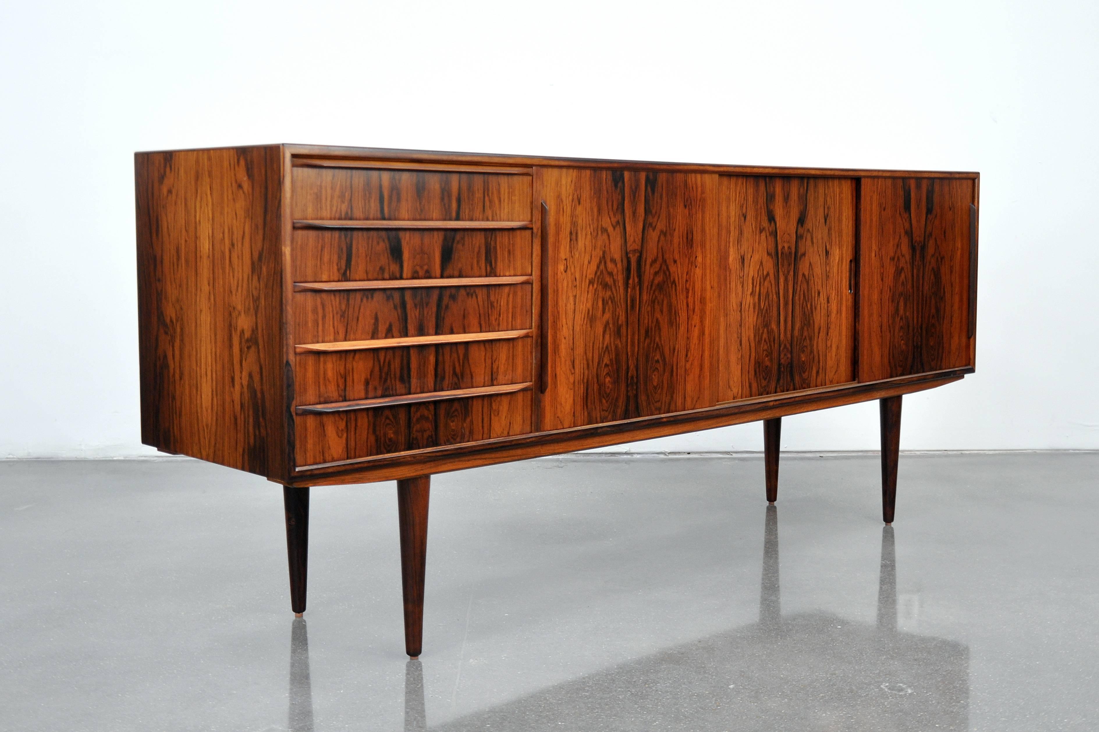 Outstanding midcentury Danish Mid-Century Modern four bay sideboard or bar cabinet made by H.P. Hansen in Randers, Denmark, and dating from the 1960s. This stunning buffet features a striking silhouette with long, slender and elegantly tapered legs.