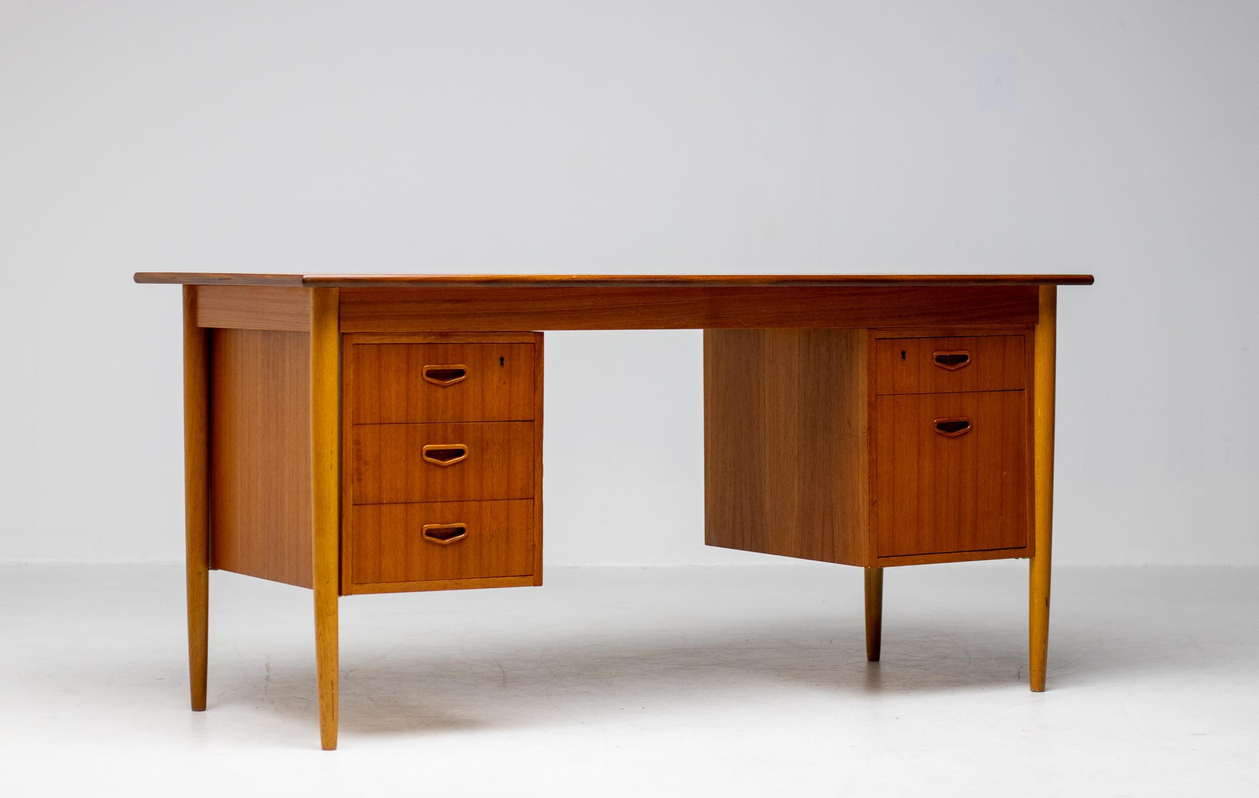 Mid-Century Danish Modern teak desk with bookcase front. Three drawers on the left and two drawers on the right. This desk was acquired from the original owner who purchased it in the 1960s. 
It is in amazingly good completely original condition.
