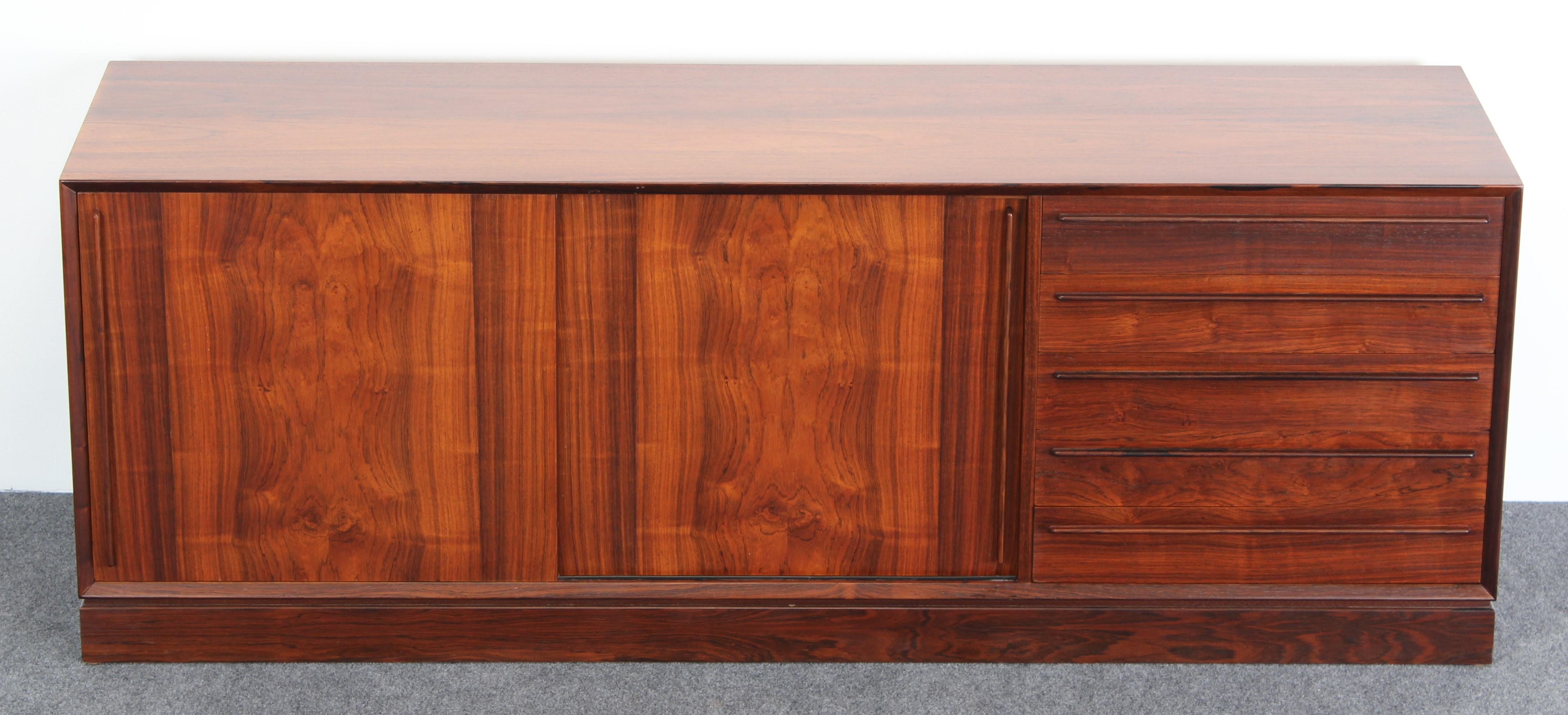 A beautiful H.P. Hansen rosewood credenza manufactured by Mobelindustri Randers in Denmark. Very versatile with five drawers and two sliding doors with two interior shelves. The sideboard is in very good condition with age appropriate