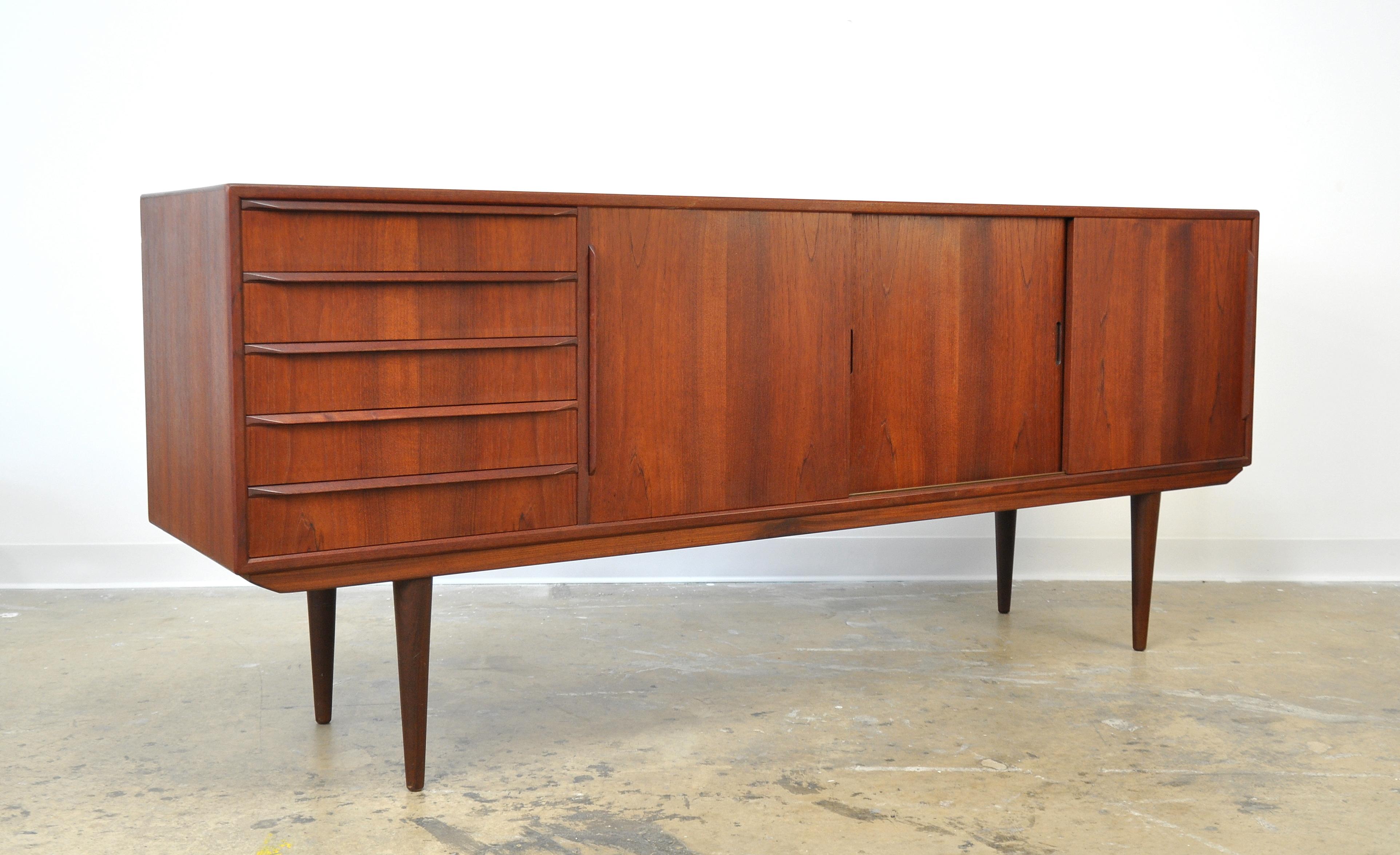 Midcentury vintage Danish modern four-bay sideboard or bar cabinet designed by Erling Torvits, dating from the 1960s. This stunning buffet features a striking silhouette with long, slender and elegantly tapered legs. Five drawers with maple interior