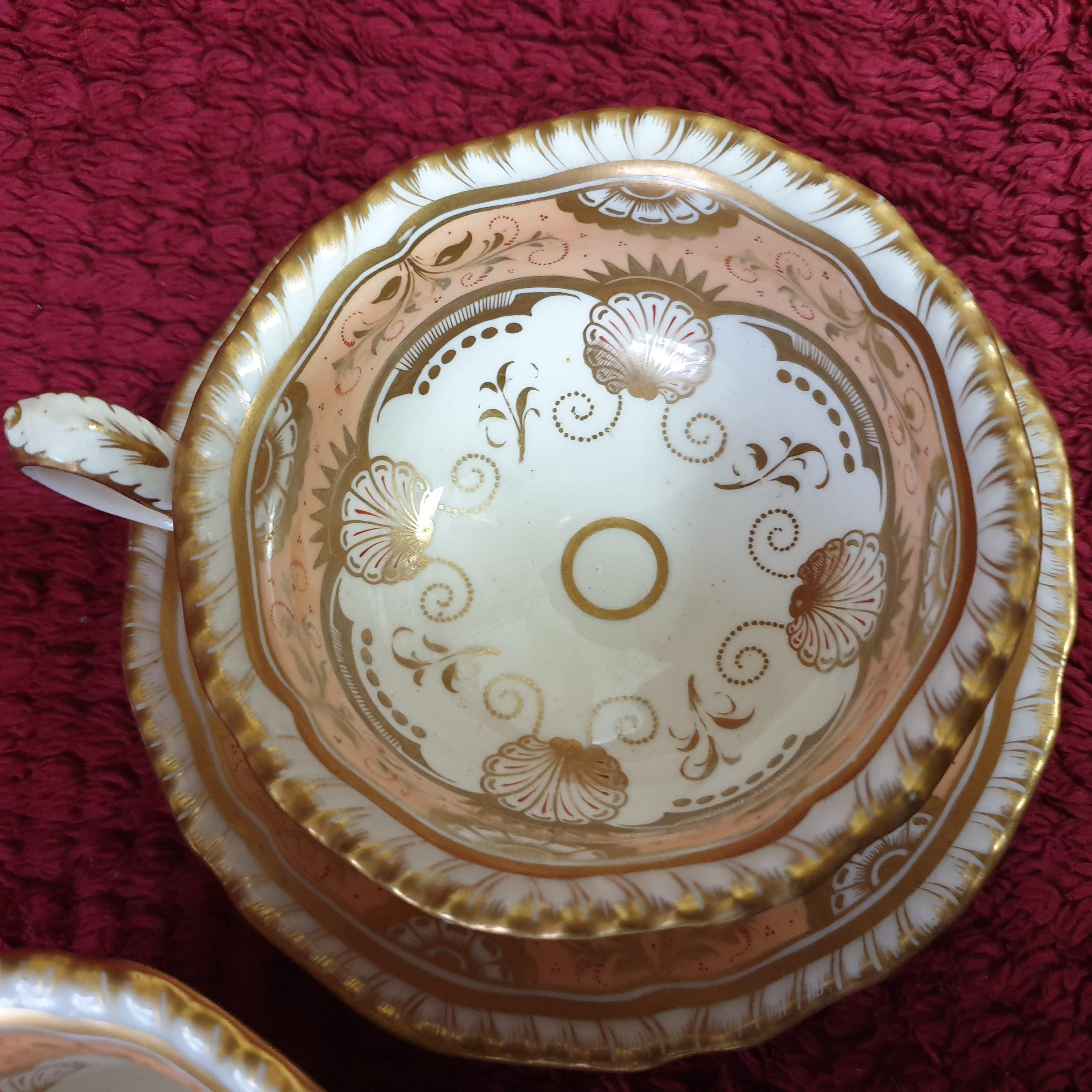 A beautiful H&R Daniel trio in the Second Gadroon shape in a salmon colour. Rounded handles with a gilt floral design with vines and leaves on the outside of both cups while the saucer and the inside of the cups is done in salmon highlighted in gilt