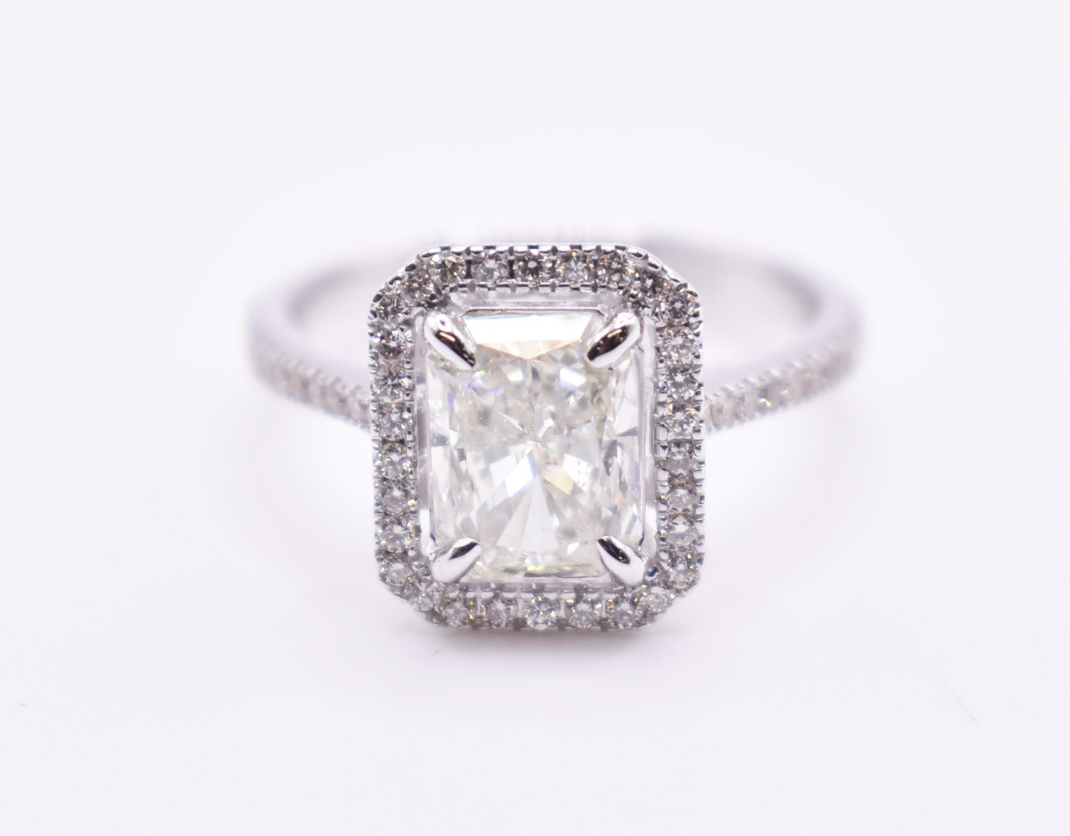 On offer for sale is a lovely radiant halo style ring, featuring a 1.80ct cushion cut diamond to the centre in a prong setting, with a halo surround adding another 0.40ct weight of diamonds.

Metal: 18K White Gold
Total Carat Weight: 2.20ct
Colour: