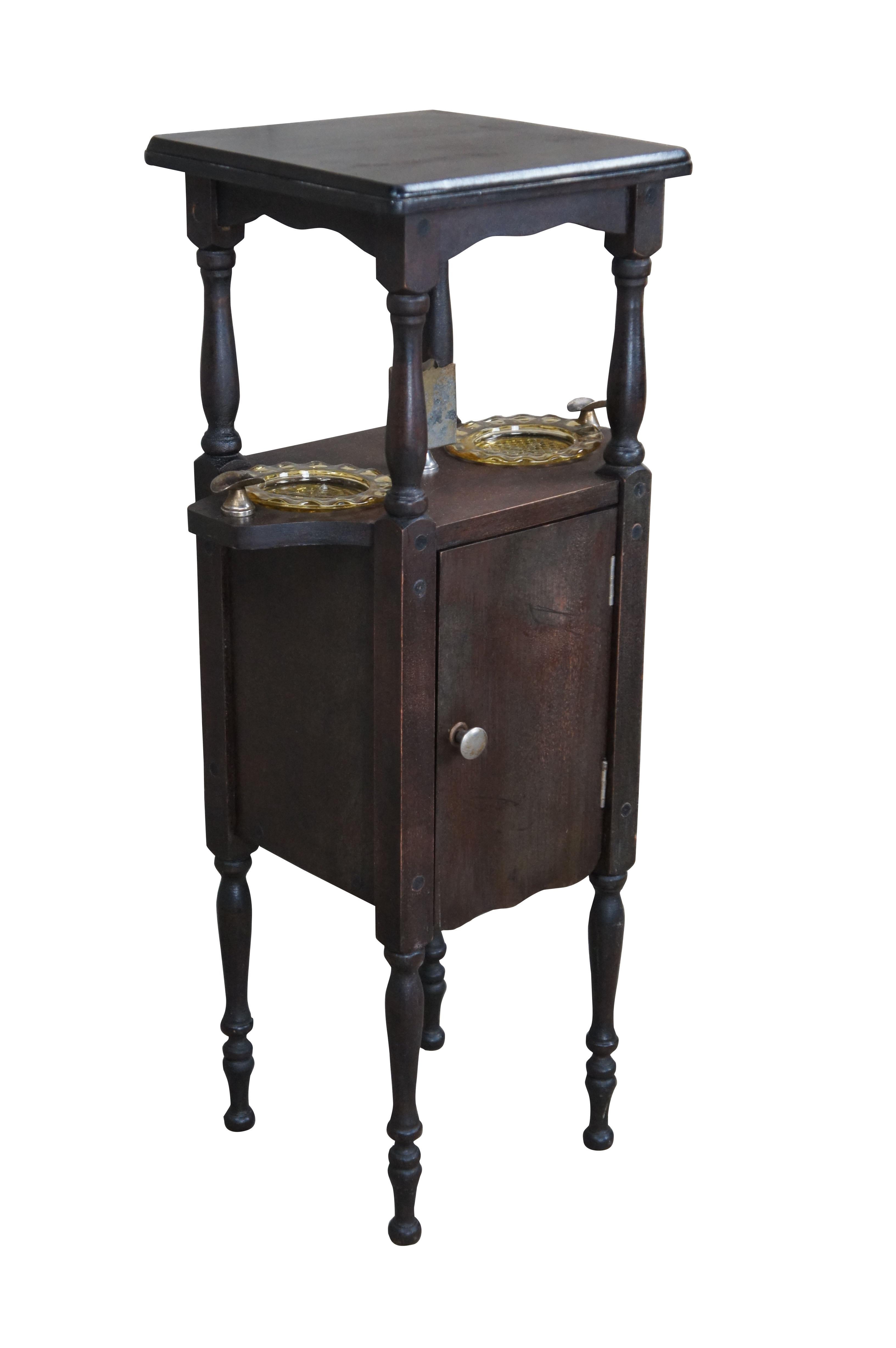 A quaint smoke stand by H.T. Cushman, circa early 20th century.  Features wooden construction with turned pots, 2 central glass ashtrays, a strike pad and lower humidor cabinet.  

Dimensions:
14