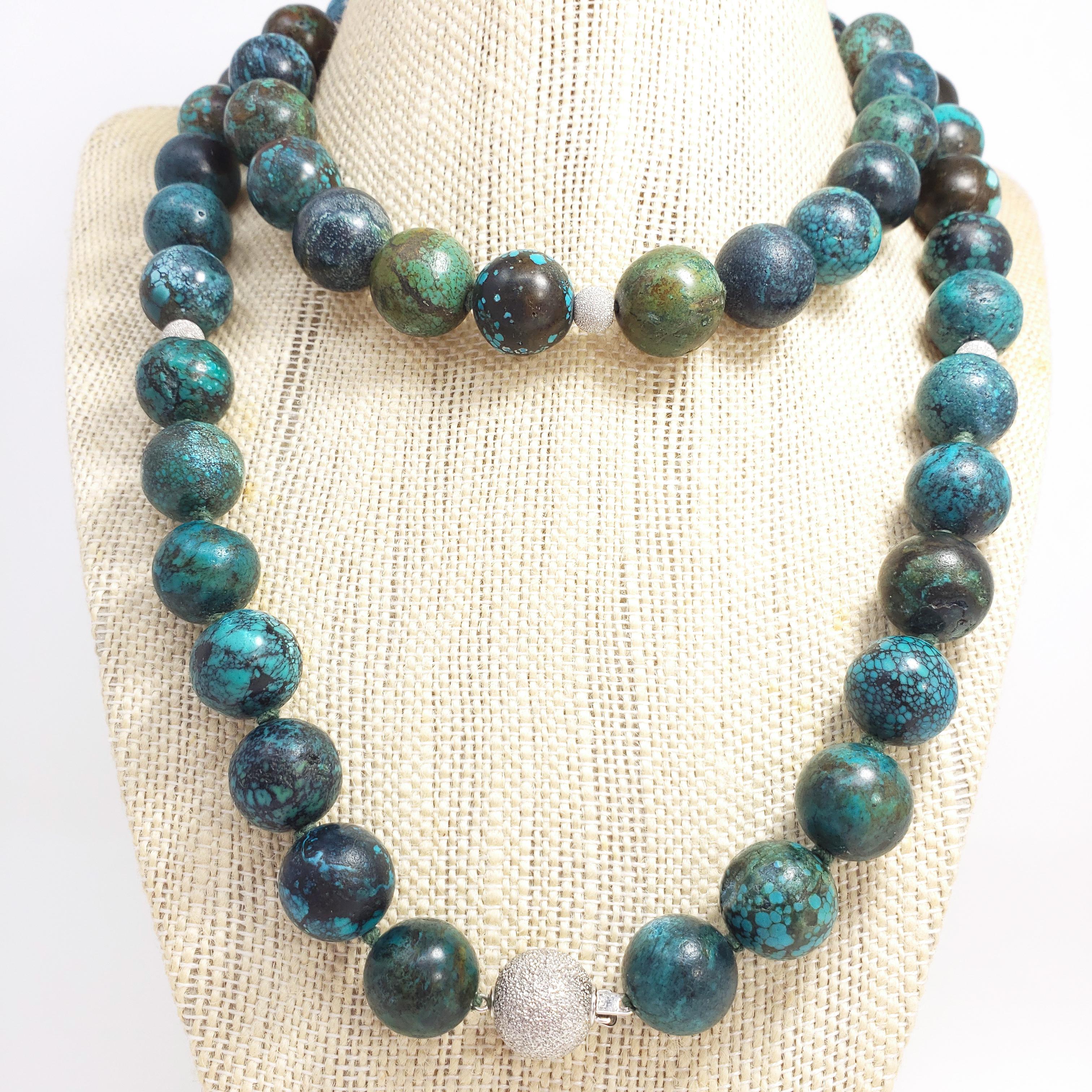 An exquisite Hubei turquoise bead necklace. This 34-inch, knotted string necklace features a series of round, 14mm, turquoise beads with exotic-looking matrix patterns. The polished gemstones are a rich, unique, and vibrant color, and are accented