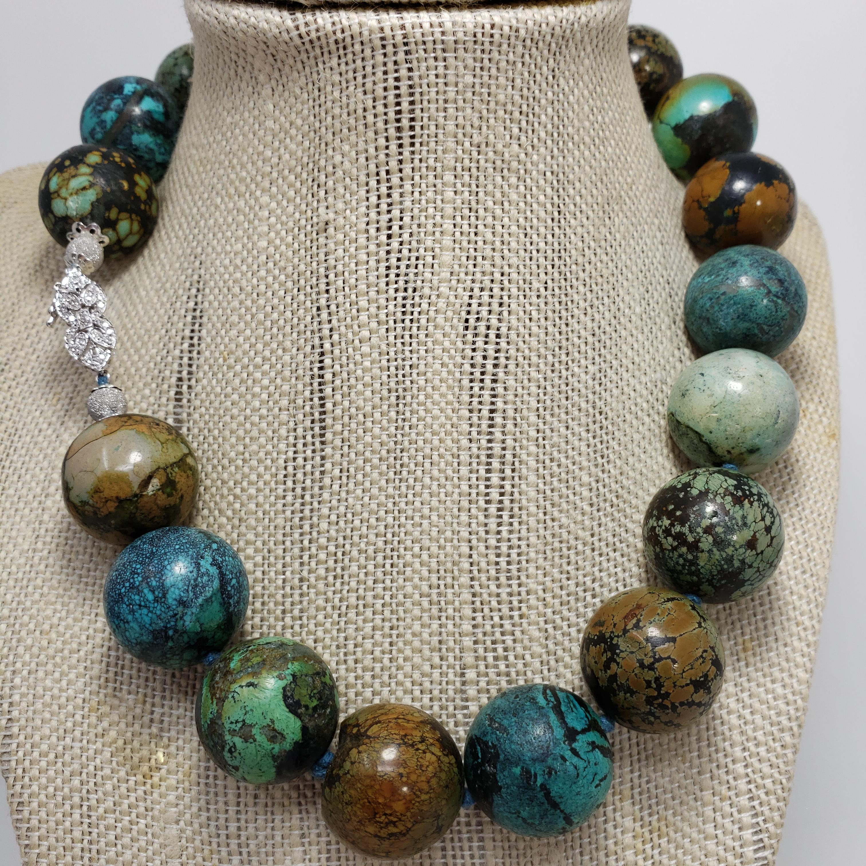 An exquisite hubei turquoise bead necklace featuring a single strand of 20mm turquoise beads in gorgeous teal, green, and earth tones. Fastened with a 14K white gold diamond-encrusted clasp, and accented with two diamond dust white gold beads. A