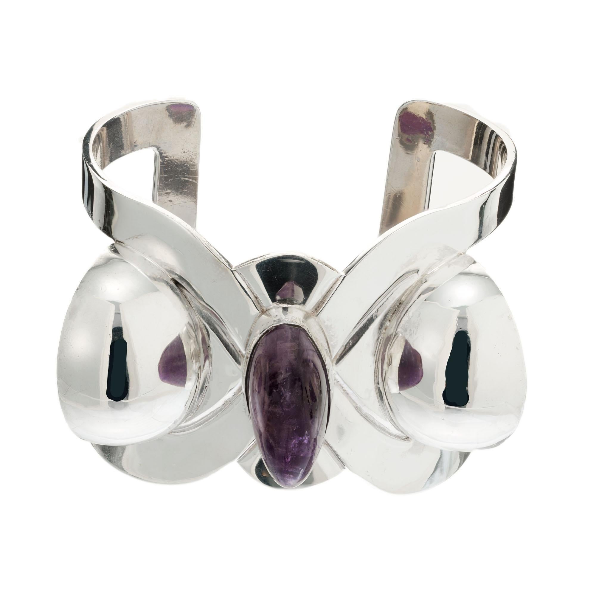 Vintage 1950's Hubert Harmon modernist Mexican sterling silver amethyst cuff bracelet. 3 Translucent natural cabochon amethyst with natural inclusions and no damage. Fits a 7 -7.5 Inch wrist.

1 oval purple muddled amethyst, approx. 35cts
2 round