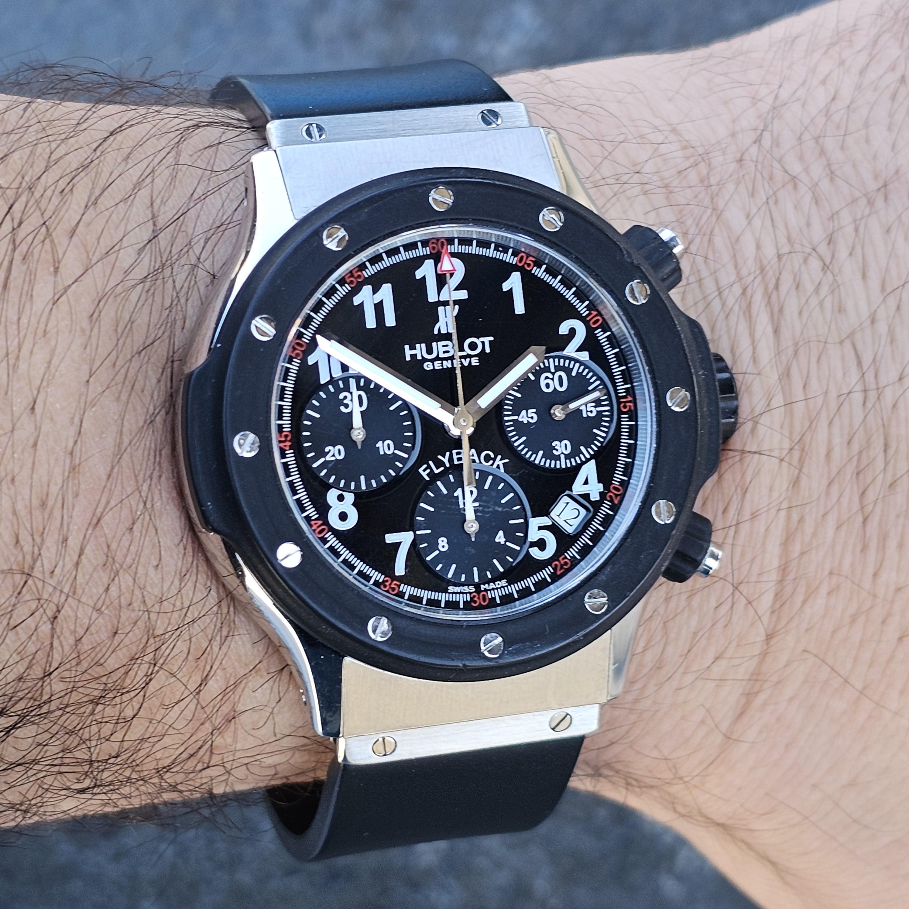 Here we have a robust Hublot Super B Black Magic watch, a striking piece with a bold design. The watch features a black dial with prominent white numerals and red accents, enhancing its readability and style. Three sub-dials highlight the